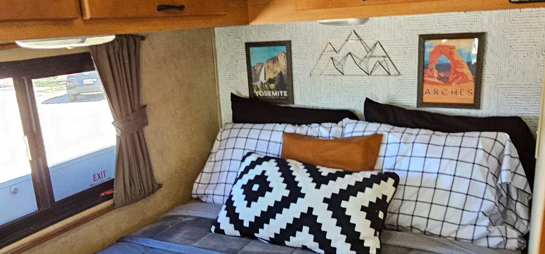 This RV rental bedroom features National Park art (Yosemite, Arches), wire mountain decor, and cozy bedding.. Thor Majestic 2014
