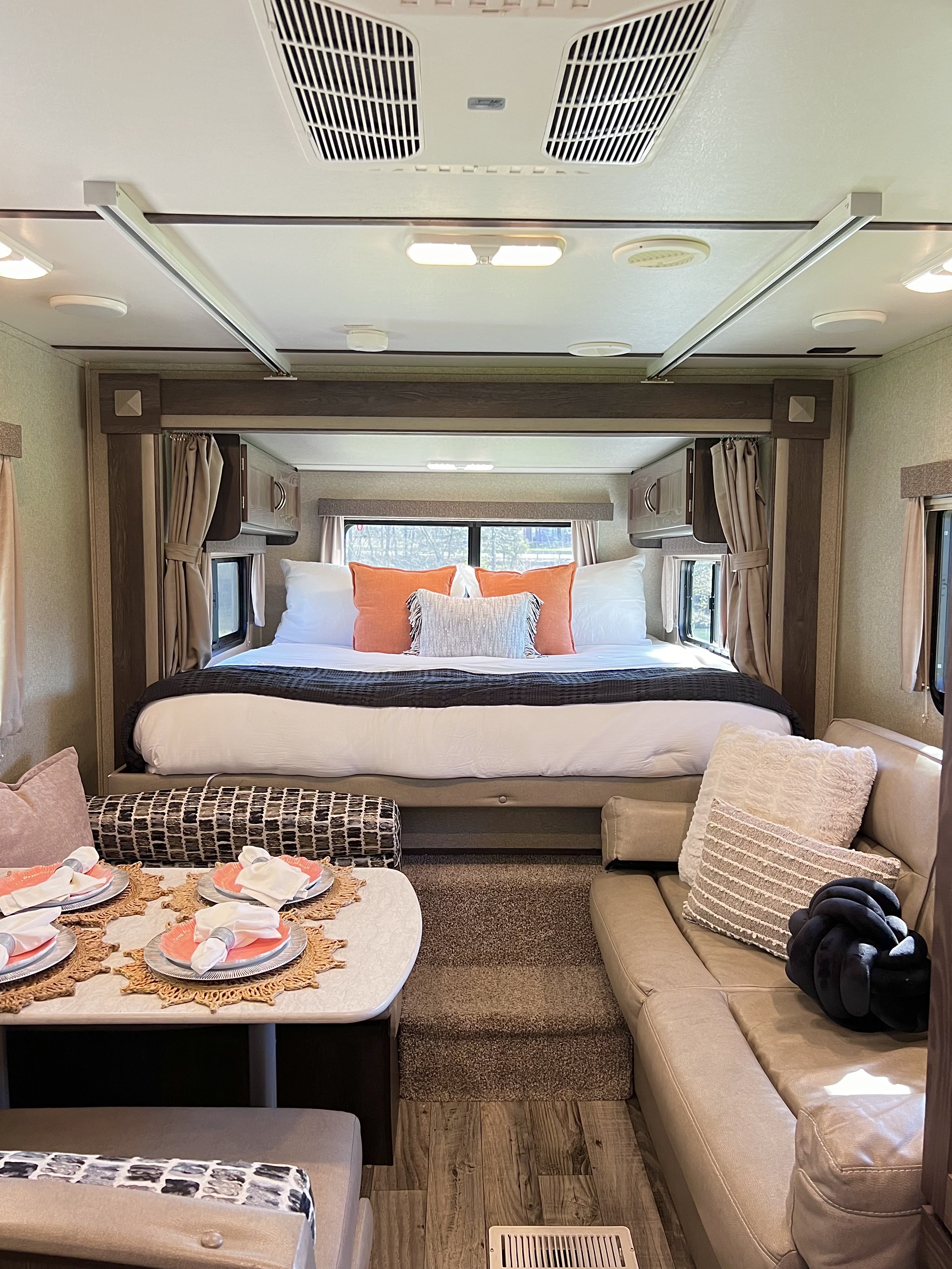 Modern RV rental interior with a spacious bedroom, dining table, and living area, featuring stylish decor and amenities.. Keystone RV Outback Ultra-Lite 2018