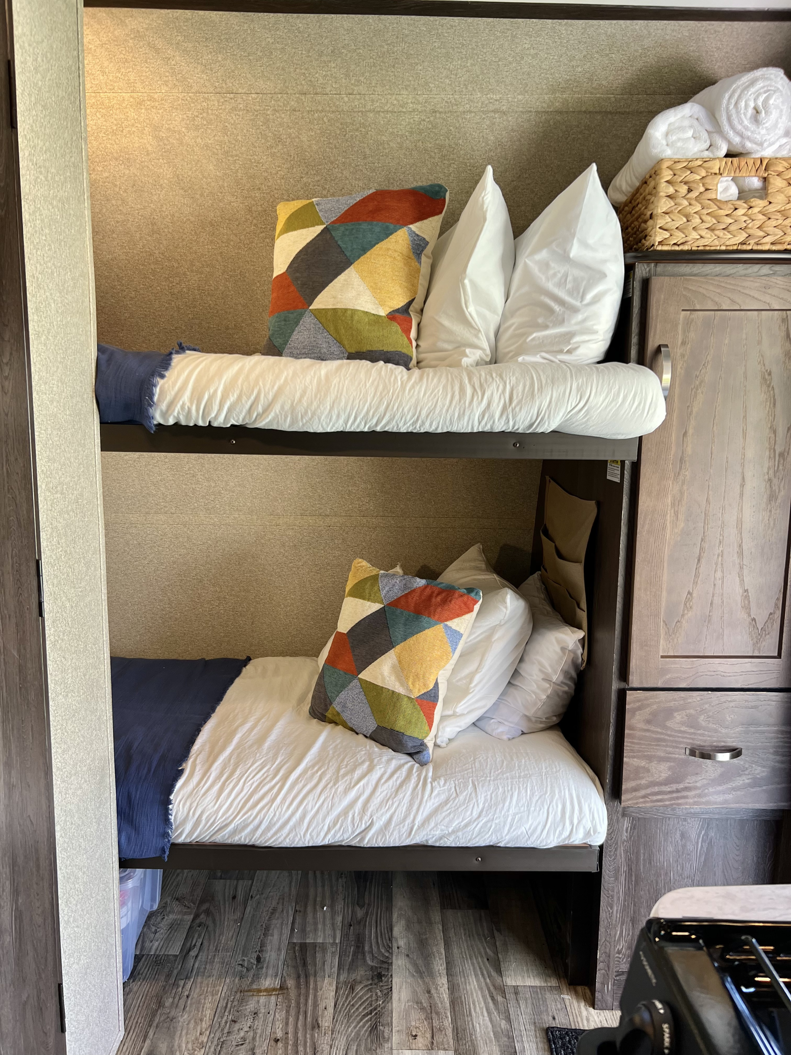 Cozy bunk beds with white linens and vibrant patterned pillows in this RV rental's comfortable sleeping area.. Keystone RV Outback Ultra-Lite 2018