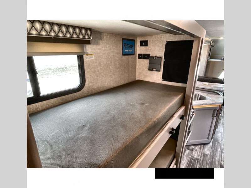 Inside this RV rental: comfortable bunk beds with a window & wall features, perfect for compact family adventures.. Thor Geneva 2023
