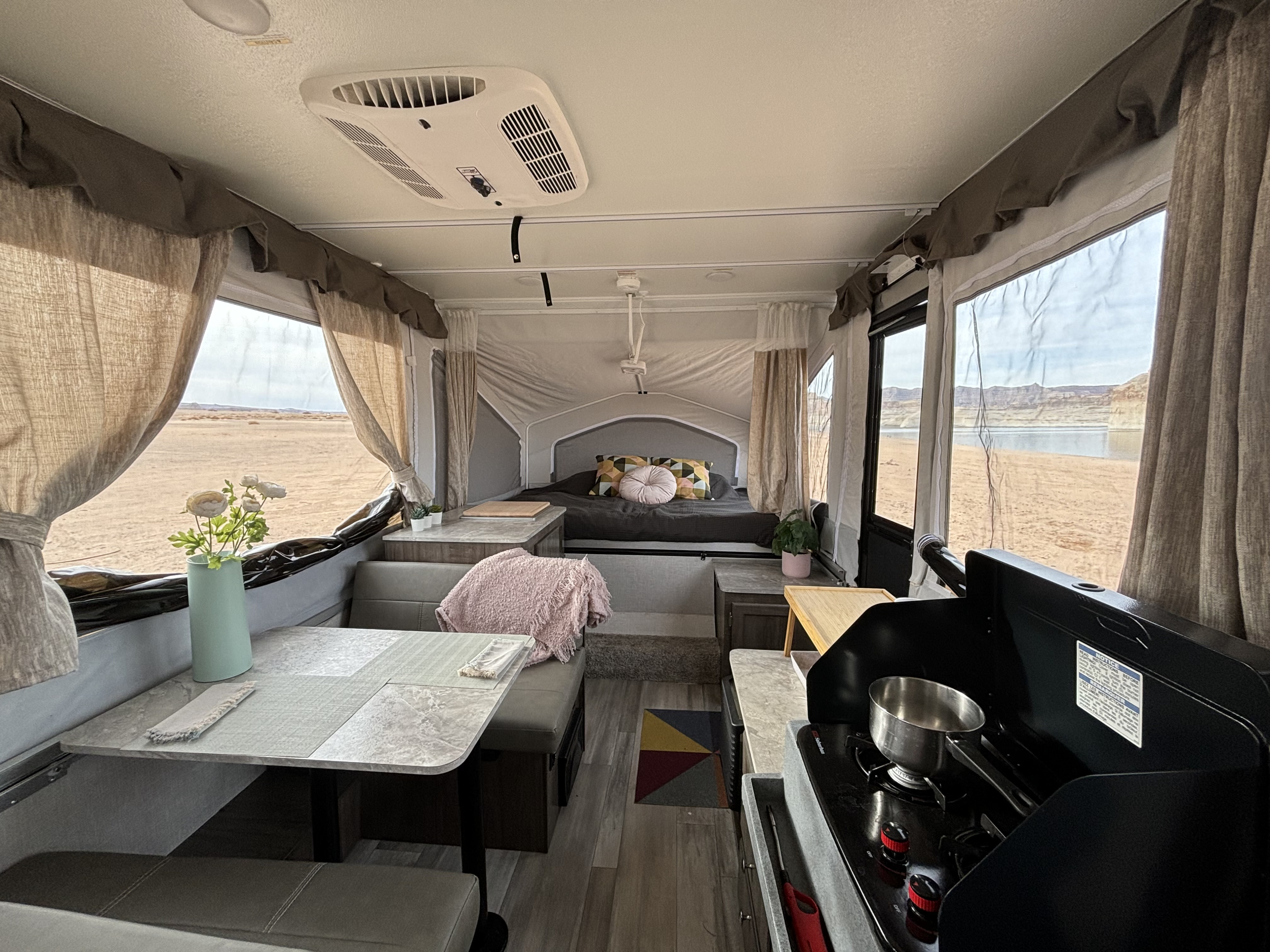 Inside a cozy rv rental, showing the dining area, bed, and kitchen with stunning desert and lake views.. Rockwood Freedom 1640LTD 2022