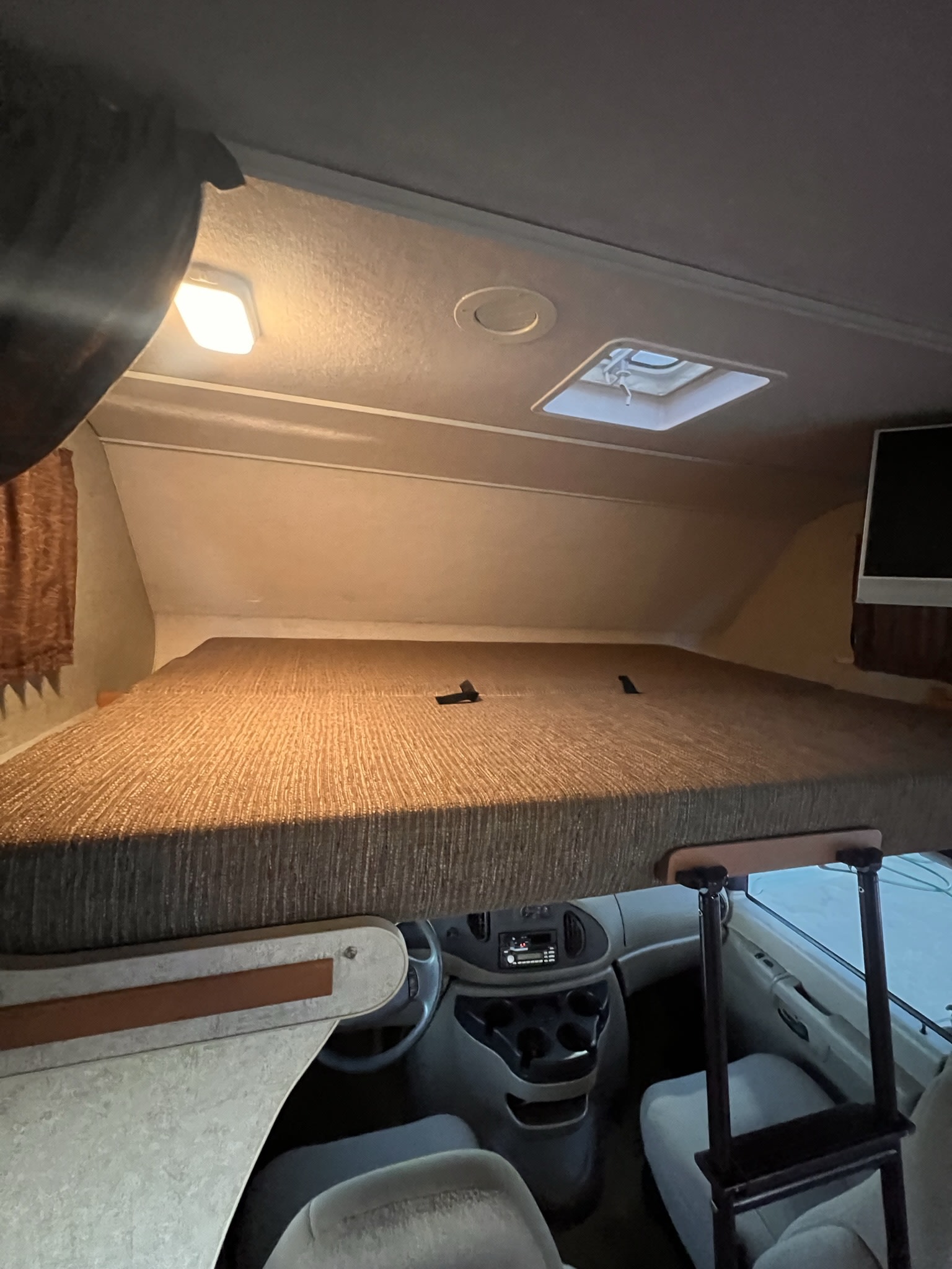 Inside an rv rental: View of the spacious over-cab bunk sleeping area and front driver's cabin with a ladder.. Winnebago Access 2008