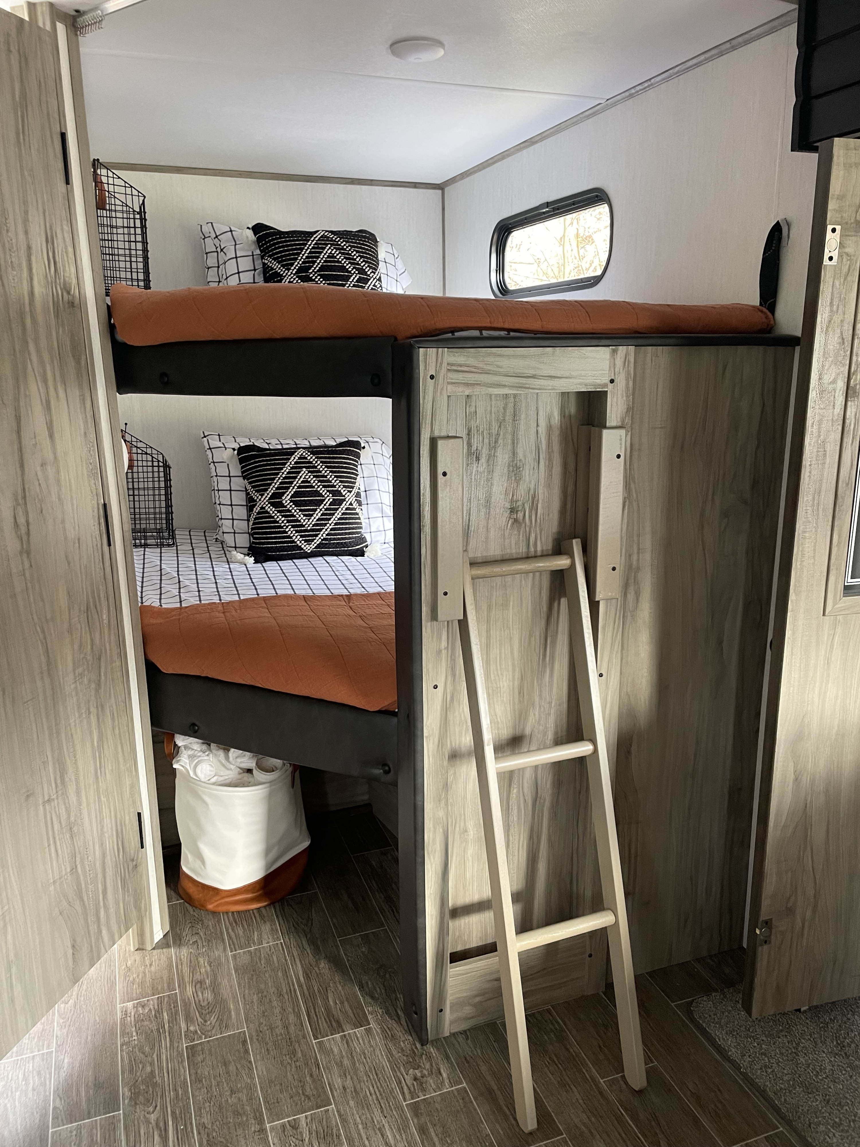 Cozy RV rental interior featuring bunk beds with a ladder, window, and wall-mounted storage for comfortable family travel.. Forest River Cherokee Alpha Wolf 2022