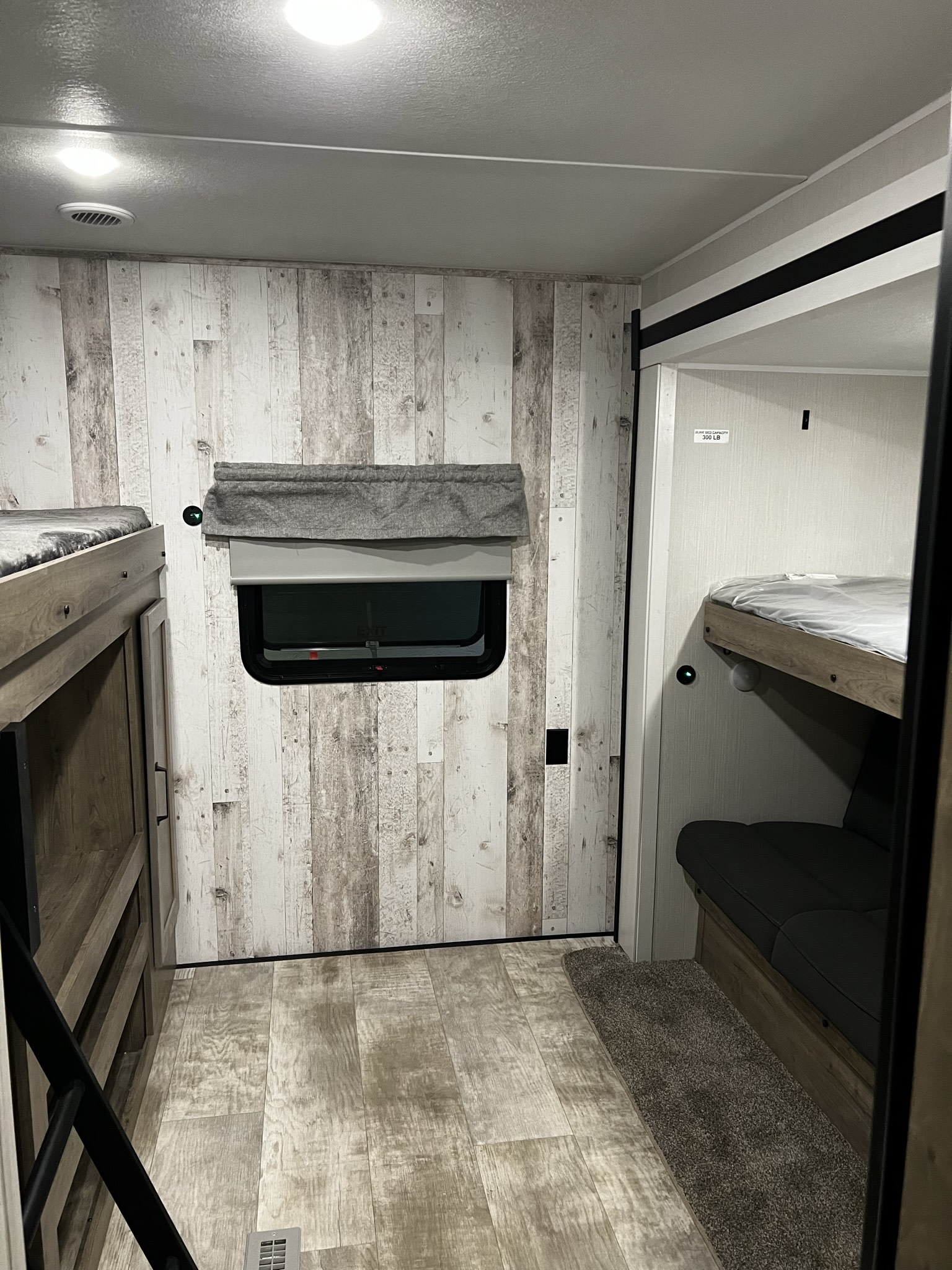 Step inside this modern RV rental bunkhouse, featuring stylish distressed wood walls, comfortable bunk beds, and a cozy sofa.. Forest River Palomino Puma 2023