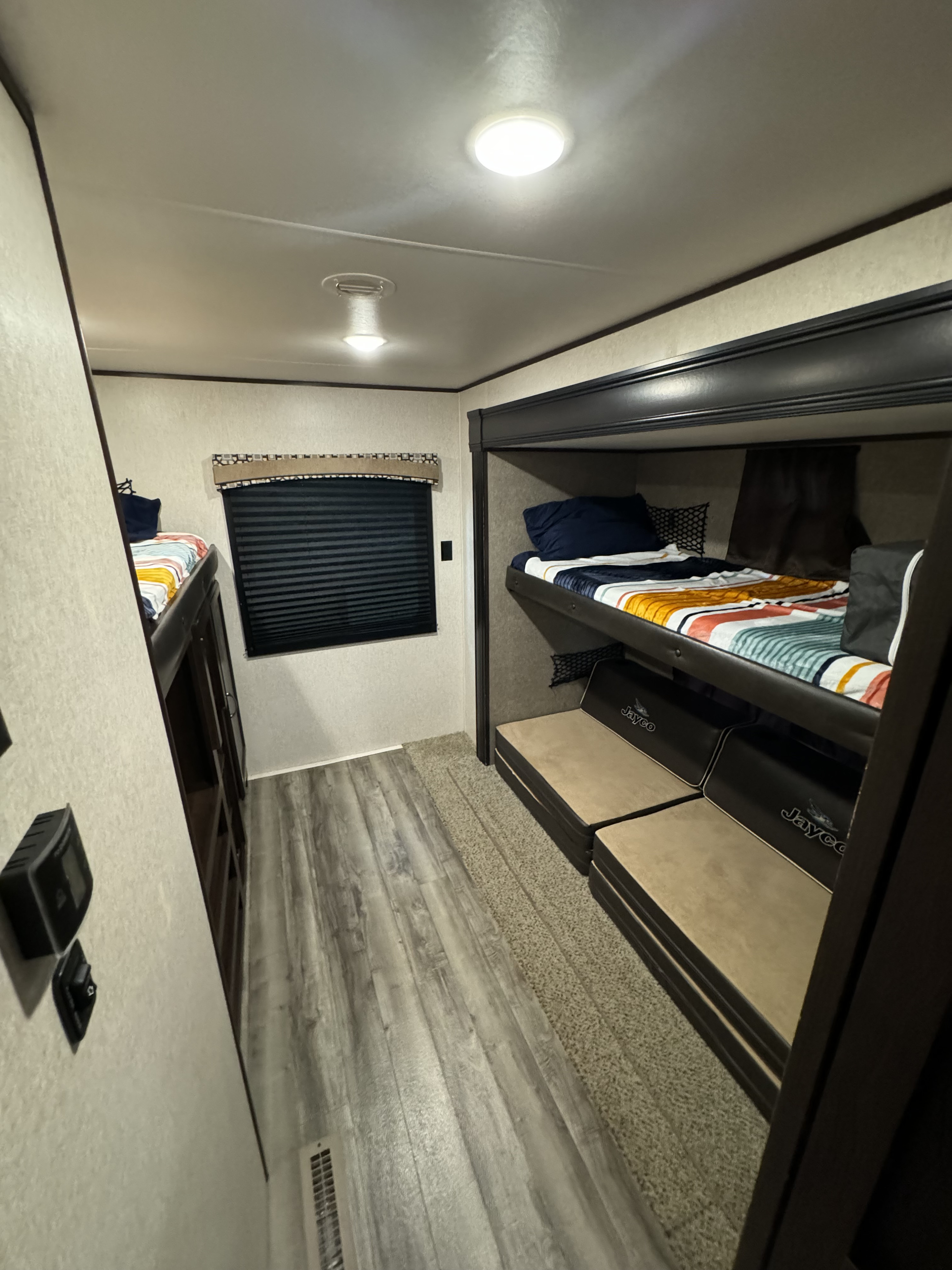 Cozy RV rental bunkhouse: A compact interior with striped bunk beds, a window, and convertible "Jayco" seating.. Jayco Jay Flight 2018
