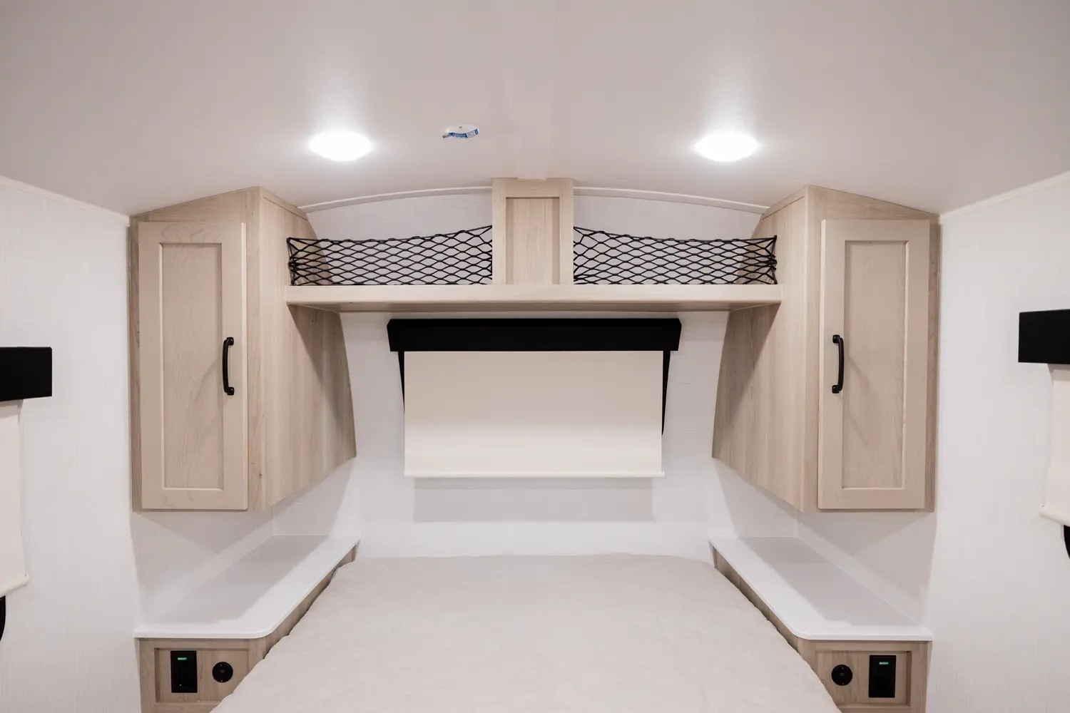 Modern RV rental bedroom with cozy bed, overhead cabinets, storage nets, and charging outlets. Ready for your adventure.. Forest River Rockwood Geo Pro 2024