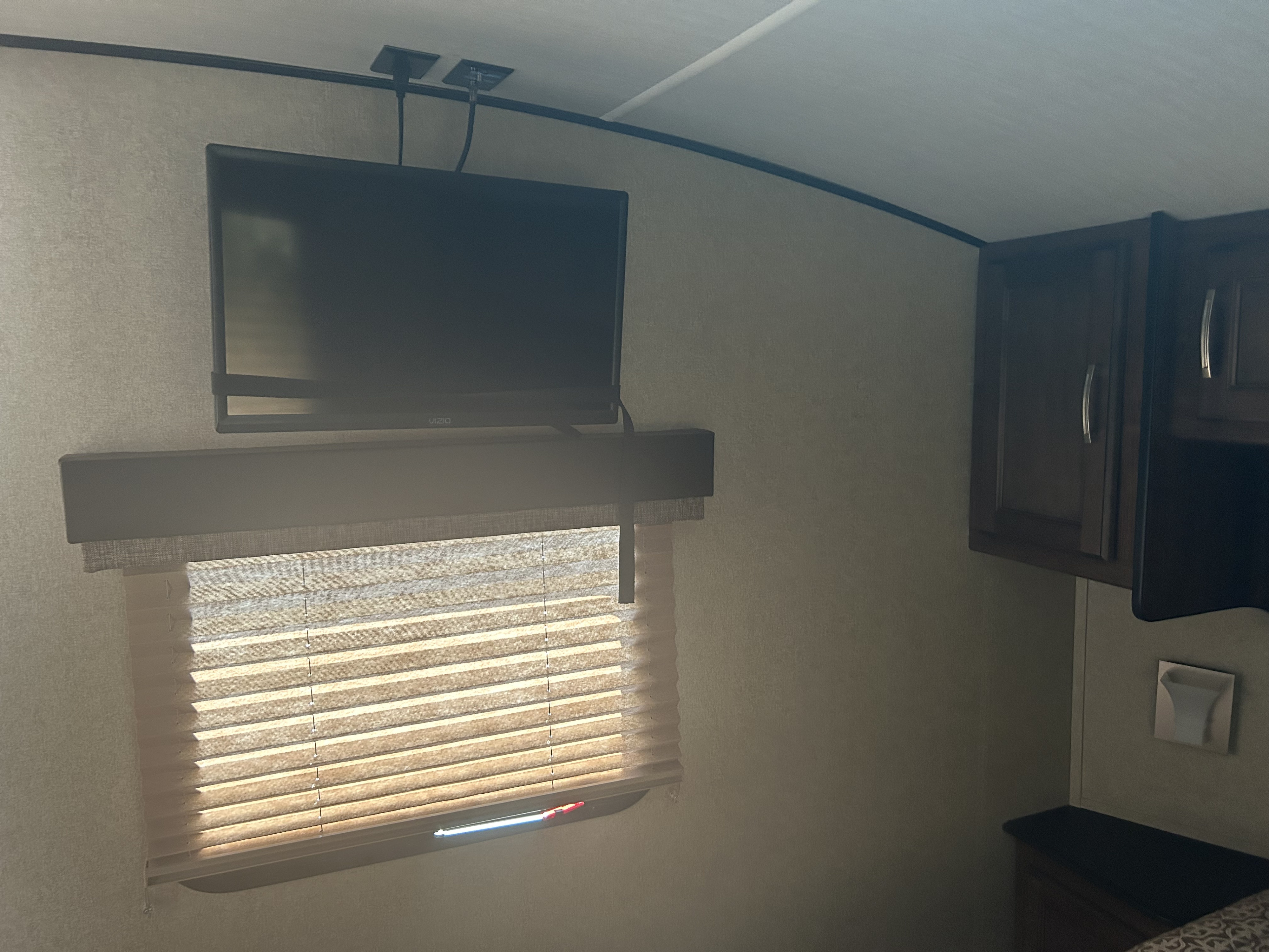 RV rental interior features a wall-mounted TV, privacy blinds, and dark cabinets. Bright and practical for travel.. Grand Design Reflection 2020