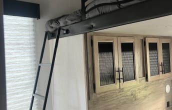 This RV rental's compact interior features a sturdy ladder to a cozy loft bed and modern storage cabinets.. Forest River Cherokee Arctic Wolf 2022