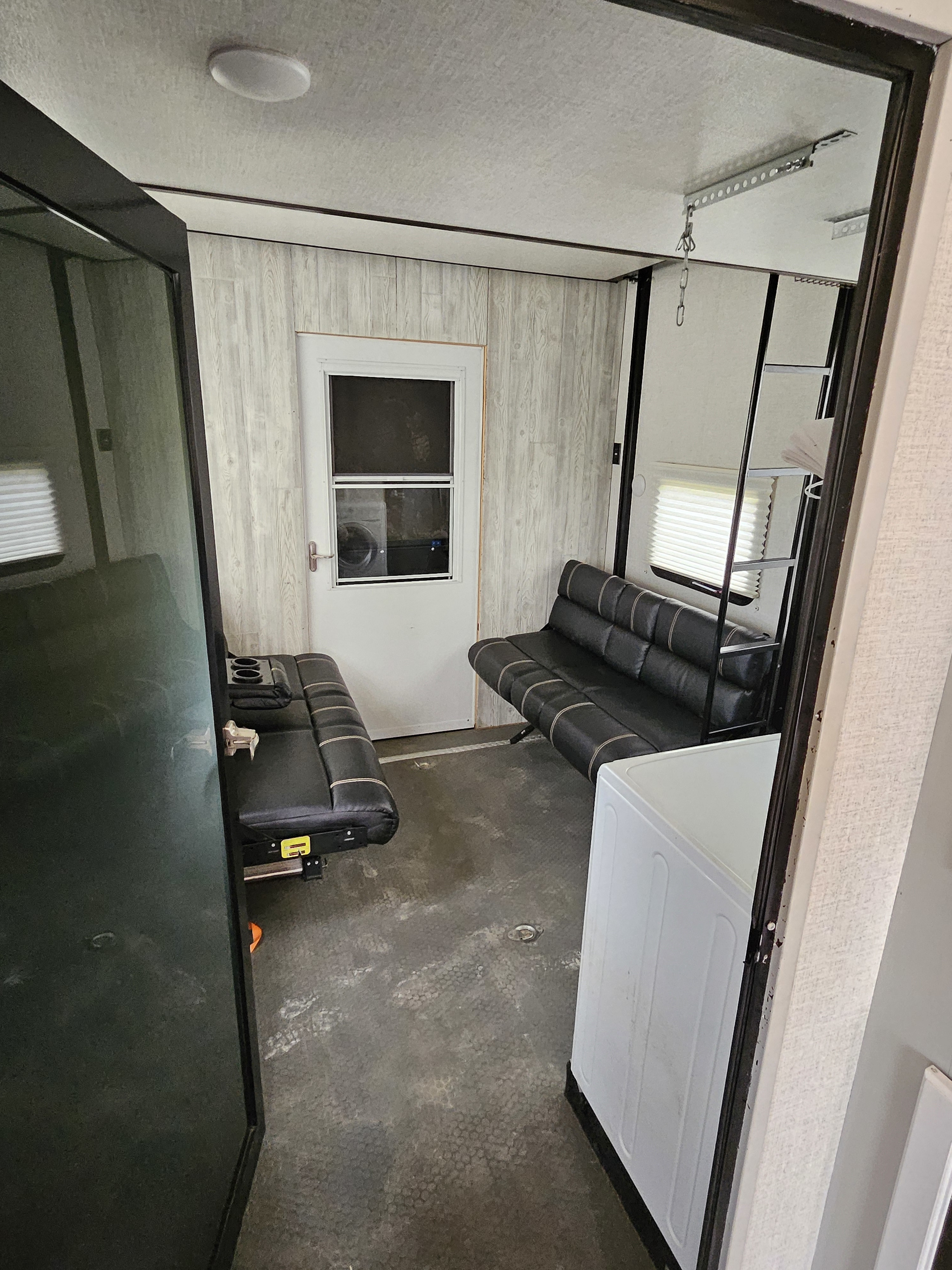 Spacious RV rental interior featuring convertible seating, a side door, rugged flooring, and a versatile layout.. Dutchmen Voltage 2020