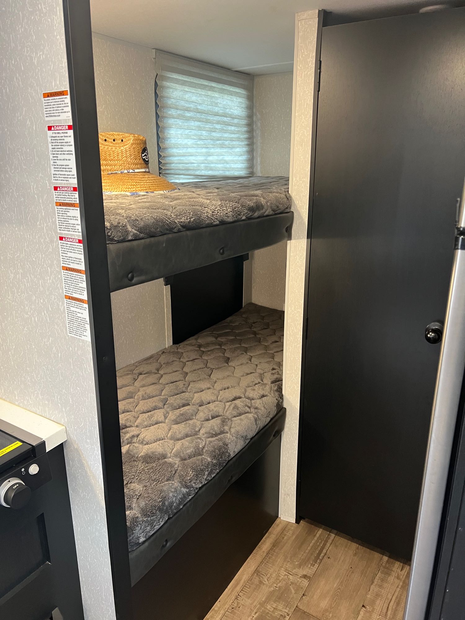RV rental interior featuring bunk beds with cozy grey mattresses, safety warnings, and a compact design. Ideal for travelers.. Forest River Cherokee Wolf Pup Black Label 2022