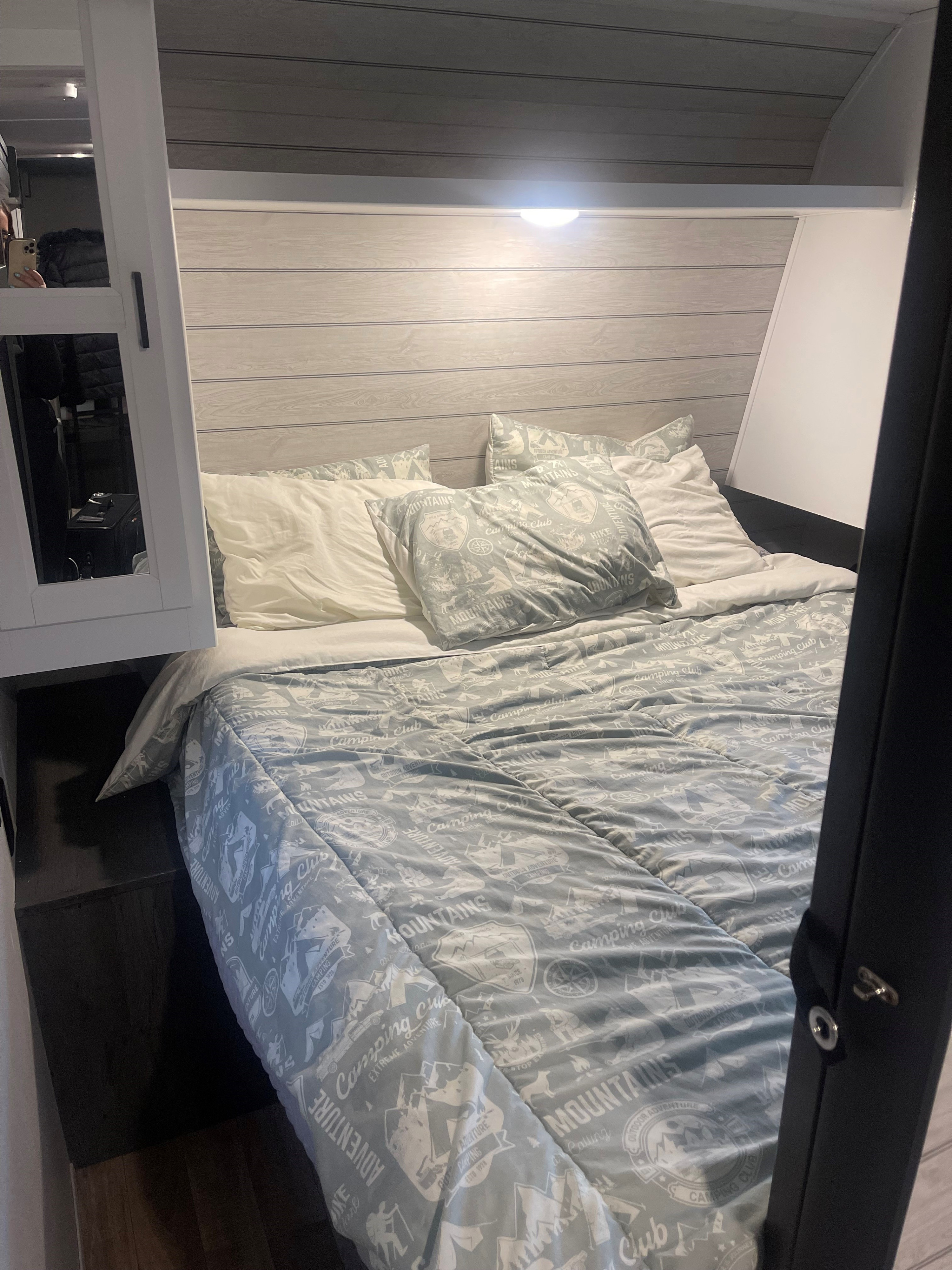 View of a neat RV rental bedroom with light wood paneling and outdoorsy-themed bedding for a restful stay.. Keystone RV Hideout 2022