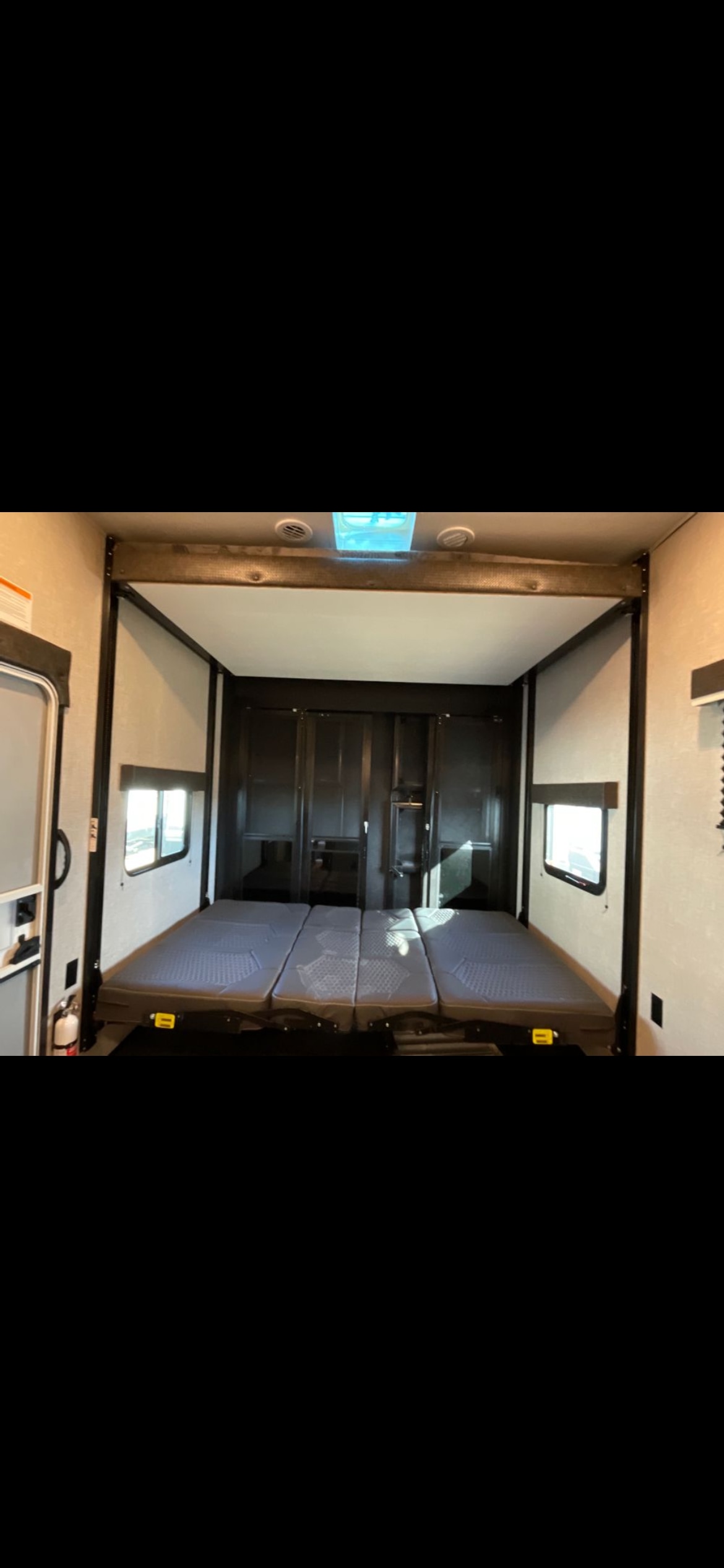 Inside a versatile RV rental toy hauler, featuring a spacious garage area with three convertible beds set up for comfortable sleeping.. Jayco Seismic 2023