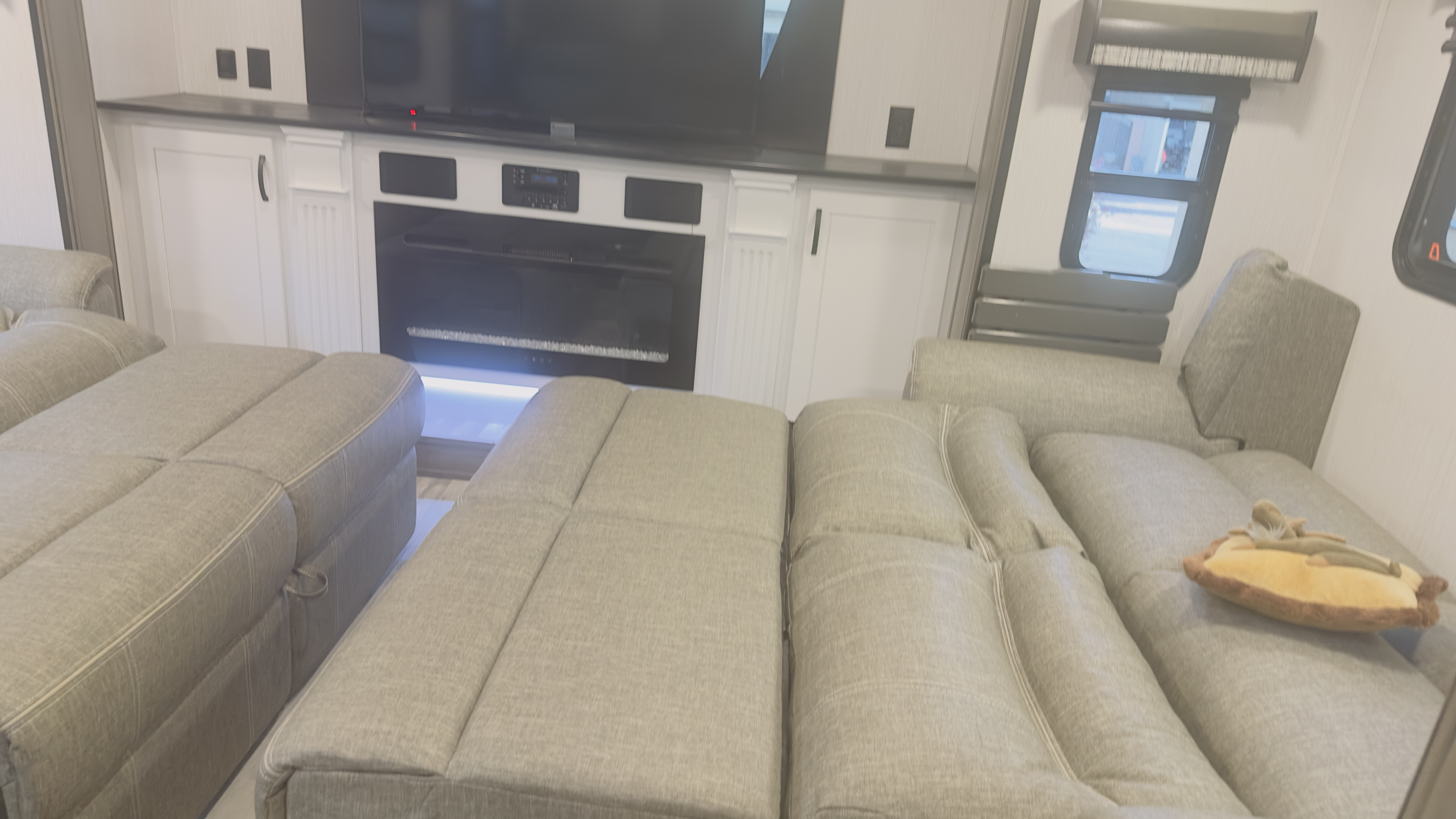 Spacious RV rental living area with comfortable pull-out sofas, TV, and fireplace, ideal for relaxation.. Cedar Creek Cedar Creek Fifth Wheel 2022