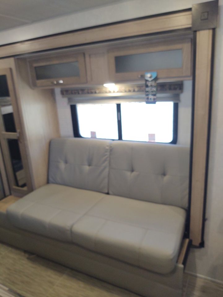 RV rental features a versatile light gray sofa, overhead cabinets, and large windows. Ideal for travel comfort.. R-Pod R-Pod Trailer 2021