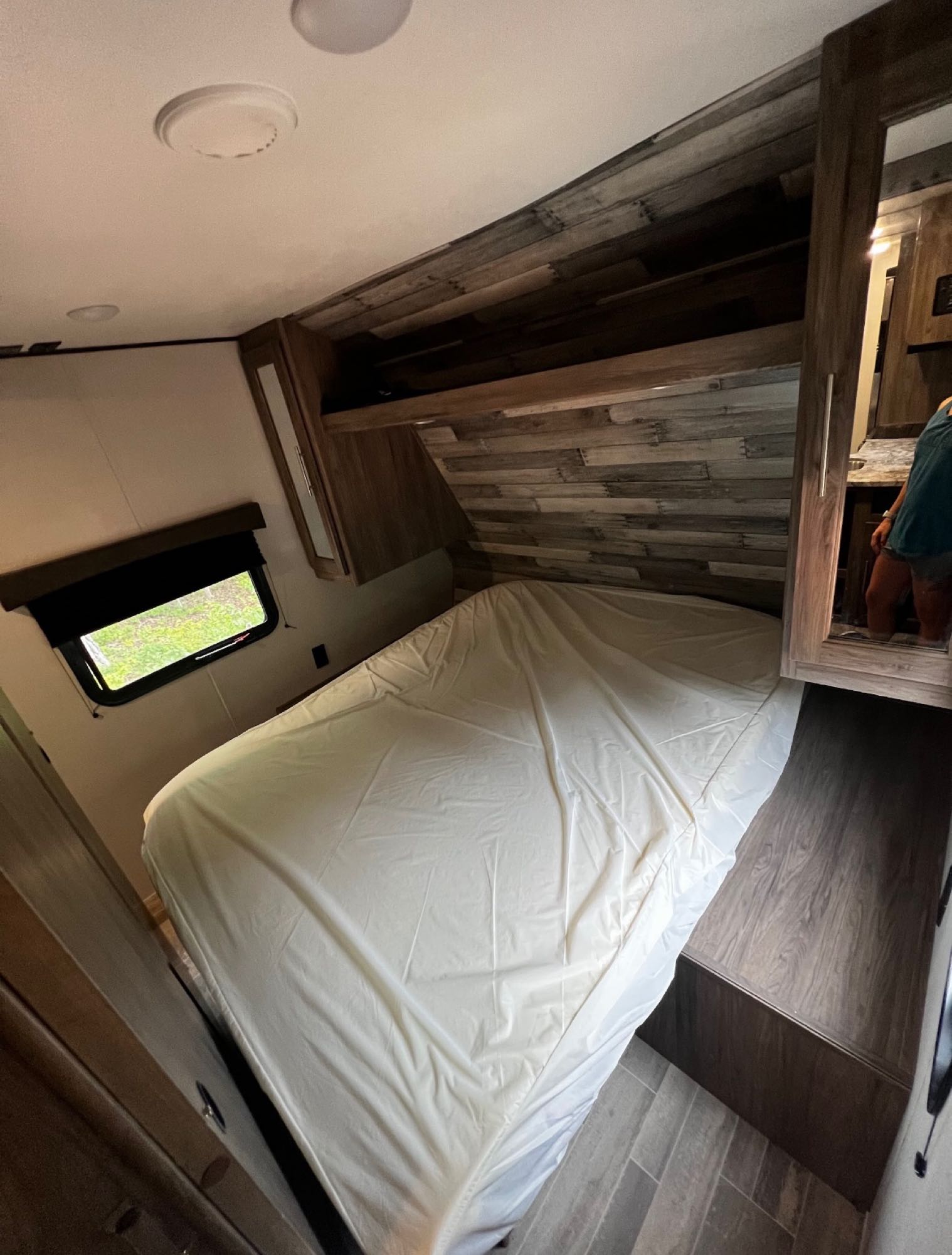 Cozy RV rental bedroom awaits, featuring a comfortable bed, wood-paneled walls, and built-in storage solutions.. Crossroads RV Zinger 2021