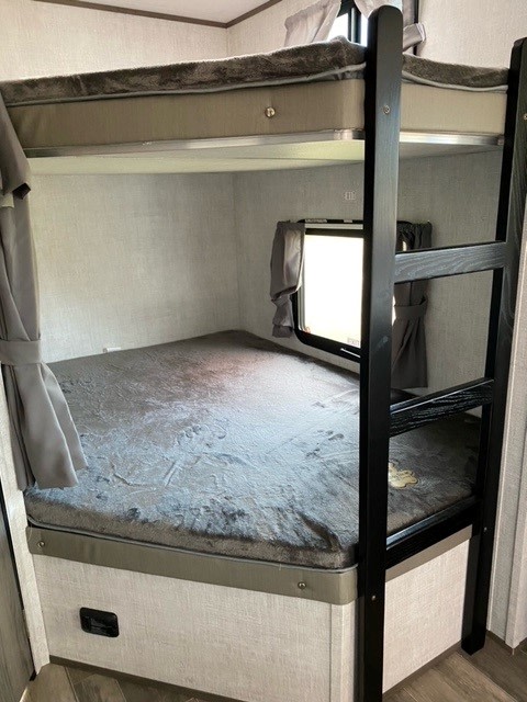 Spacious bunk beds in this cozy RV rental sleeping area, complete with a ladder and window, ideal for families and friends.. Gulf Stream Gulf Breeze 2023