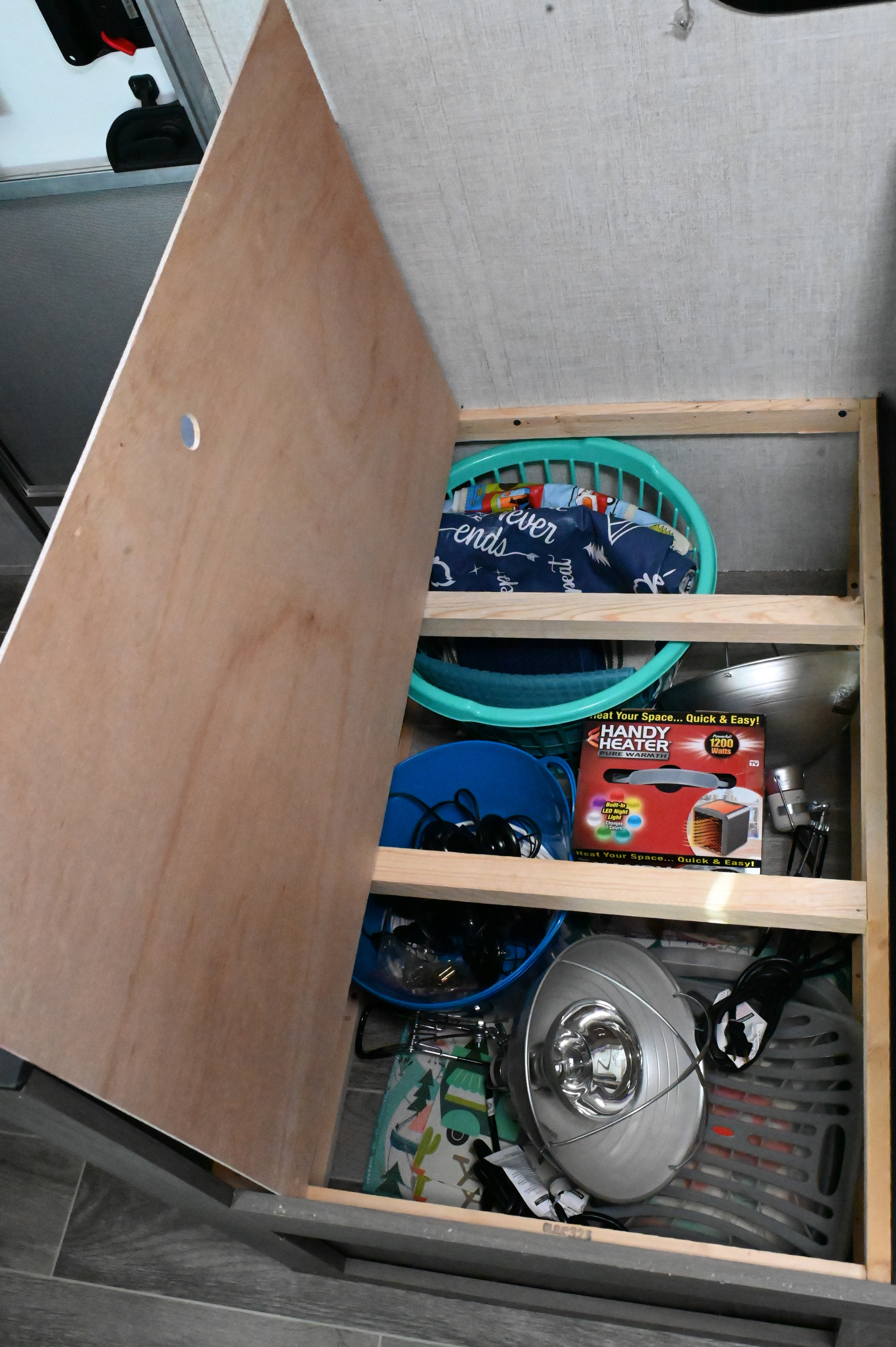 RV rental storage: Organized interior cabinet with shelves, baskets, and a portable heater, optimizing space in a camper.. Gulf Stream Ameri-Lite Super Lite 2021