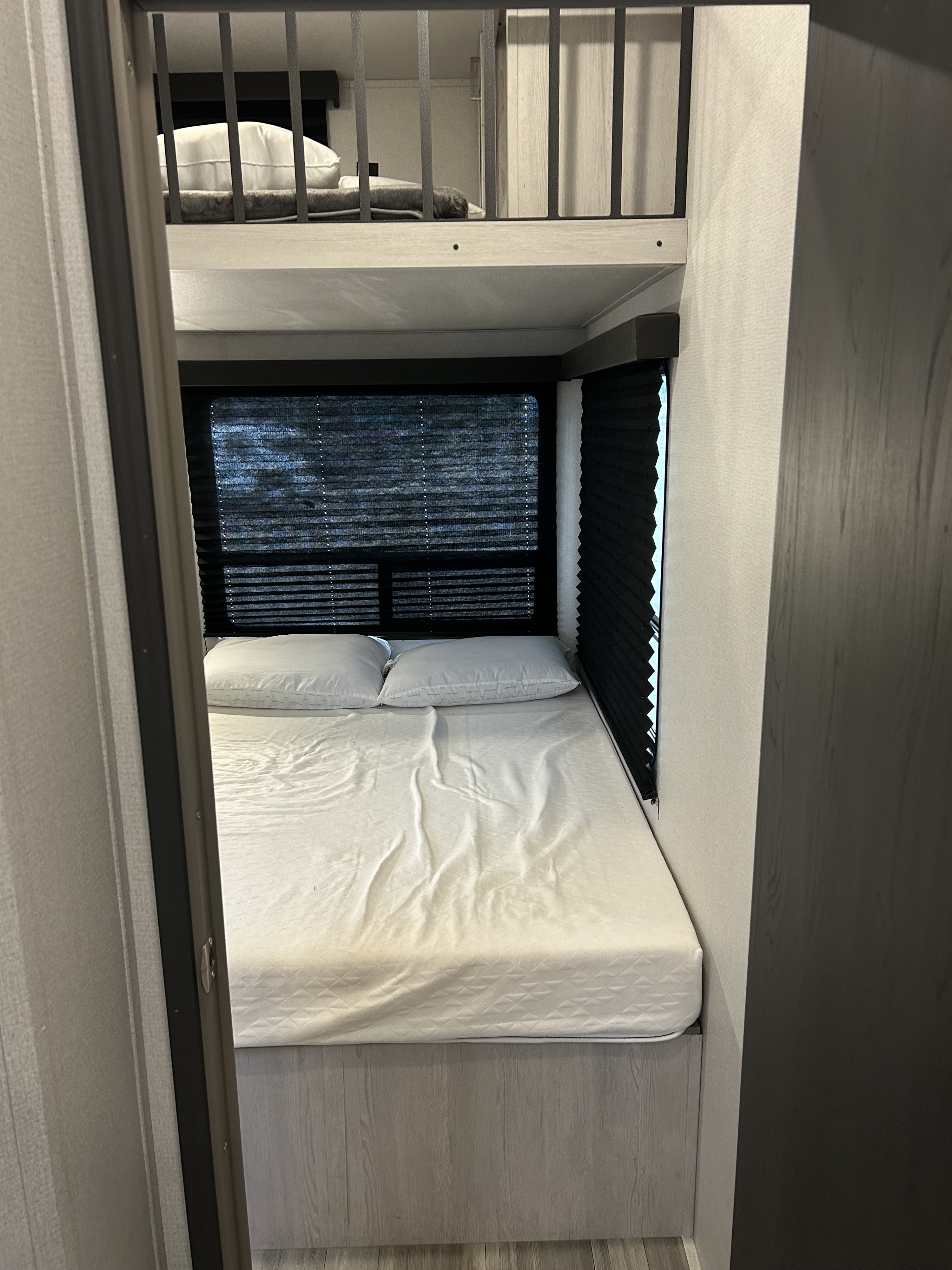 RV rental bedroom with a comfortable lower bed, an upper loft bunk, and windows with black privacy blinds.. Keystone Sprinter 2022