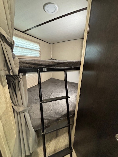 RV rental bunk beds provide a cozy sleeping area. Features a ladder, window, and privacy curtains for travel comfort.. Coachmen Spirt 2021