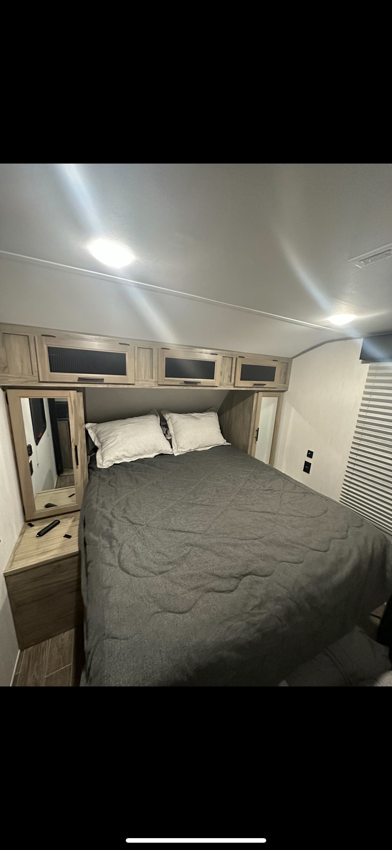 Step inside this RV rental bedroom with a comfortable bed, mirrored wardrobes, and ample overhead cabinets. Ideal compact living space.. Forest River Cherokee Alpha Wolf 2022