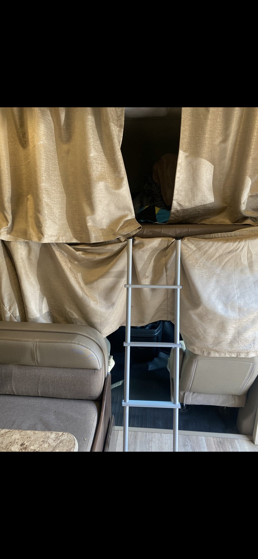 RV rental interior with a cozy bunk bed, gold privacy curtains, and a metal ladder.. Thor Four Winds 2018