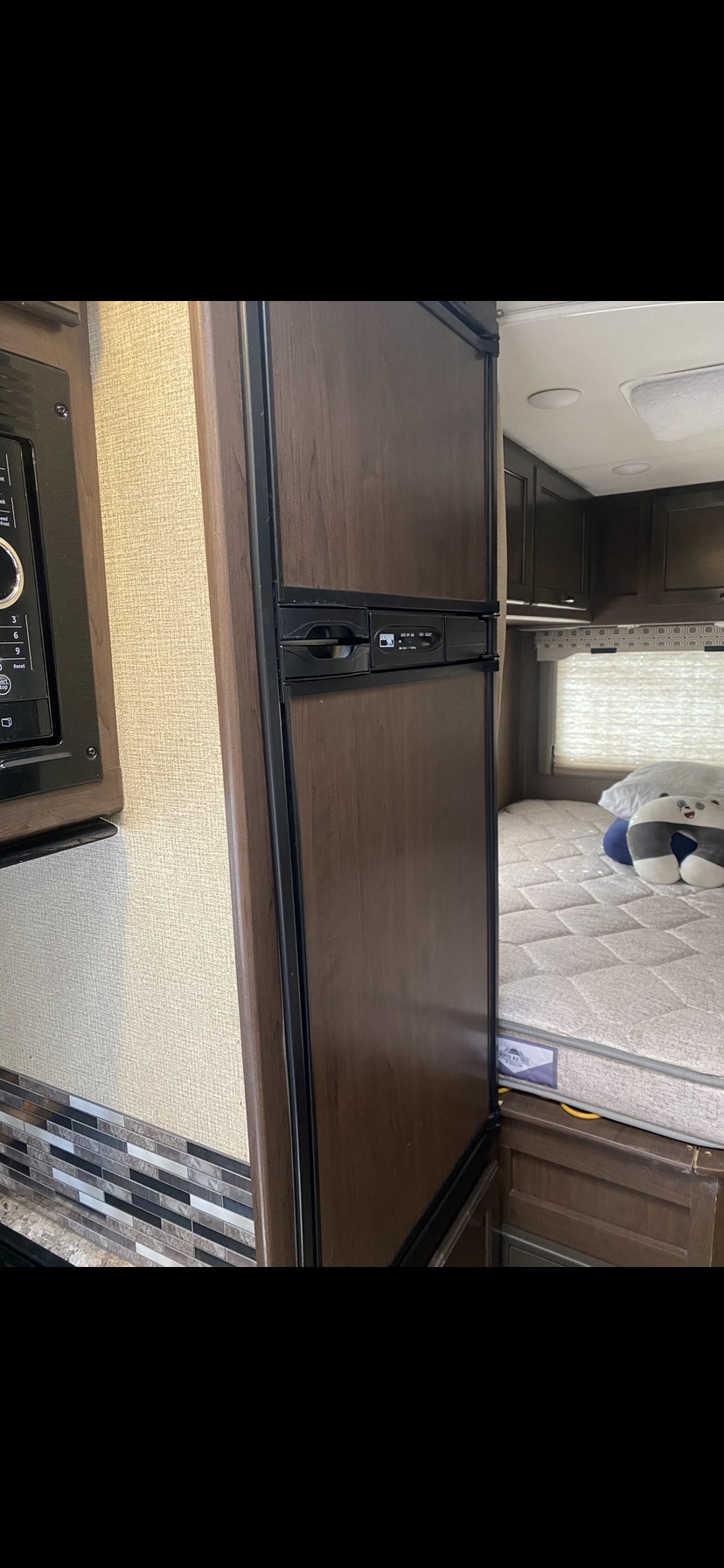 RV rental interior showing a microwave & refrigerator, leading to a sleeping area with a mattress.. Thor Four Winds 2018