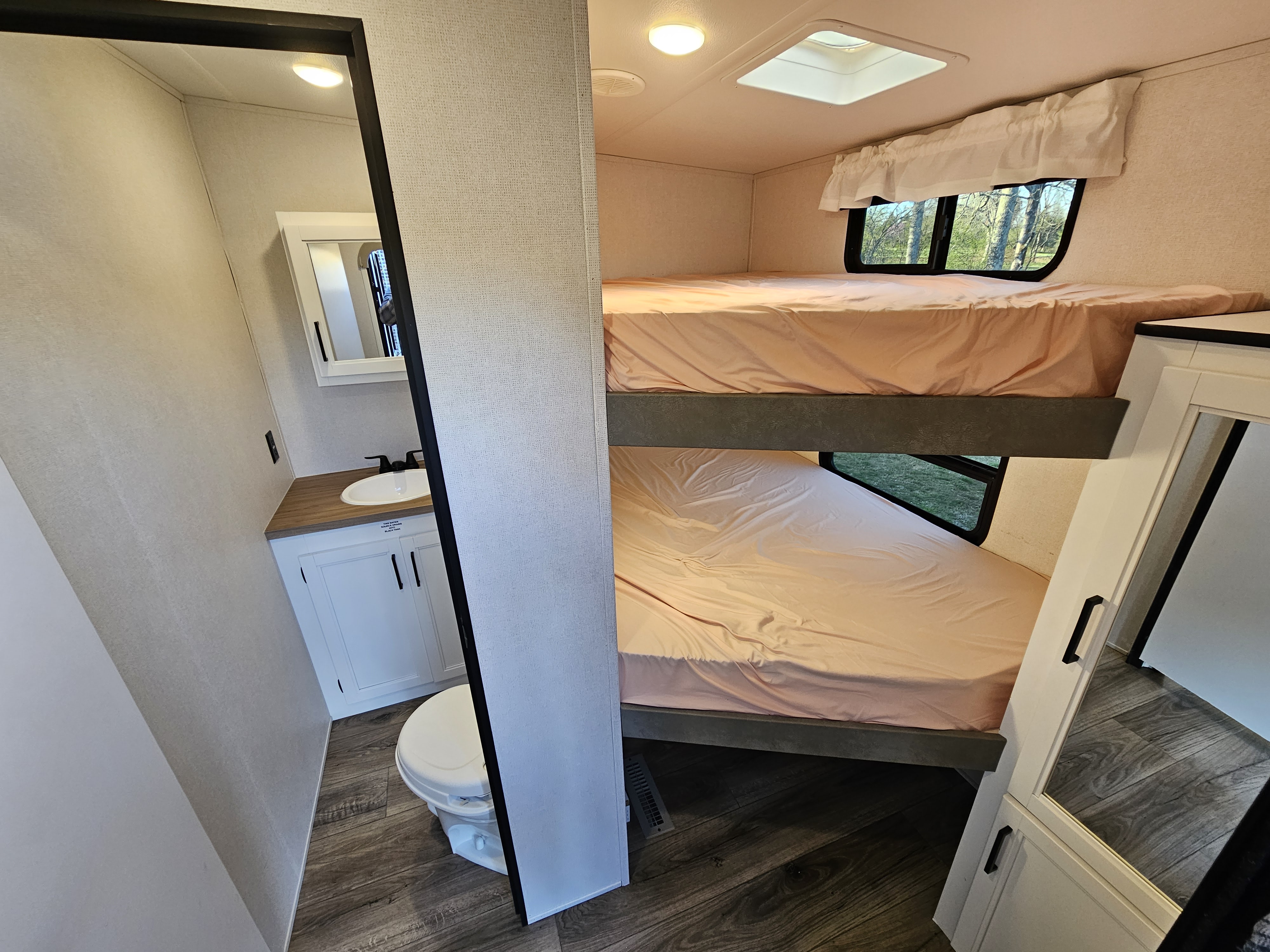 An RV rental interior: compact bathroom with toilet and sink, adjacent to cozy bunk beds.. Crusader Lite 2022