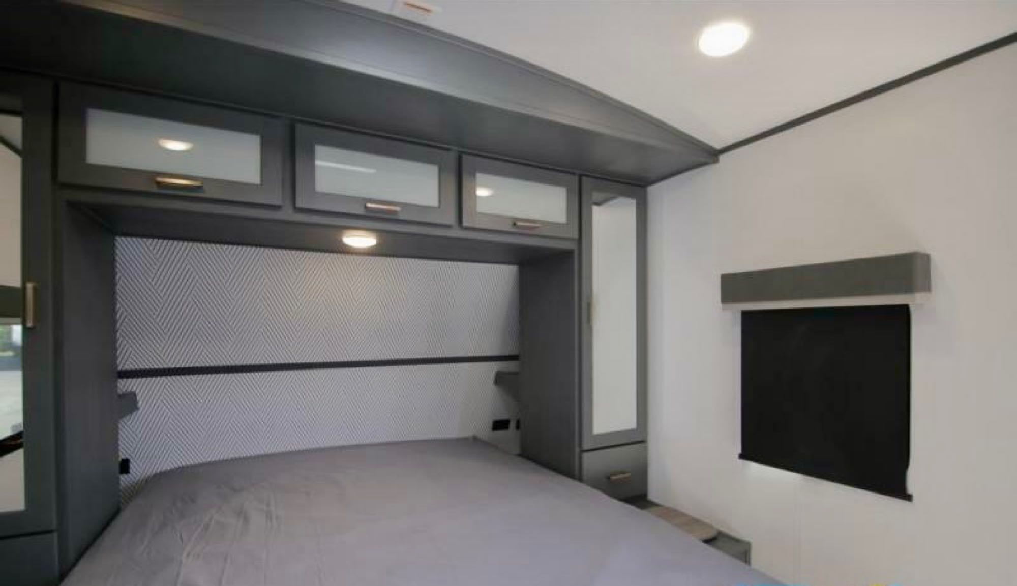 RV rental bedroom showcasing a gray bed, overhead storage, patterned headboard, and a window with blinds.. Keystone RV Bullet Premier Ultra Lite 2022