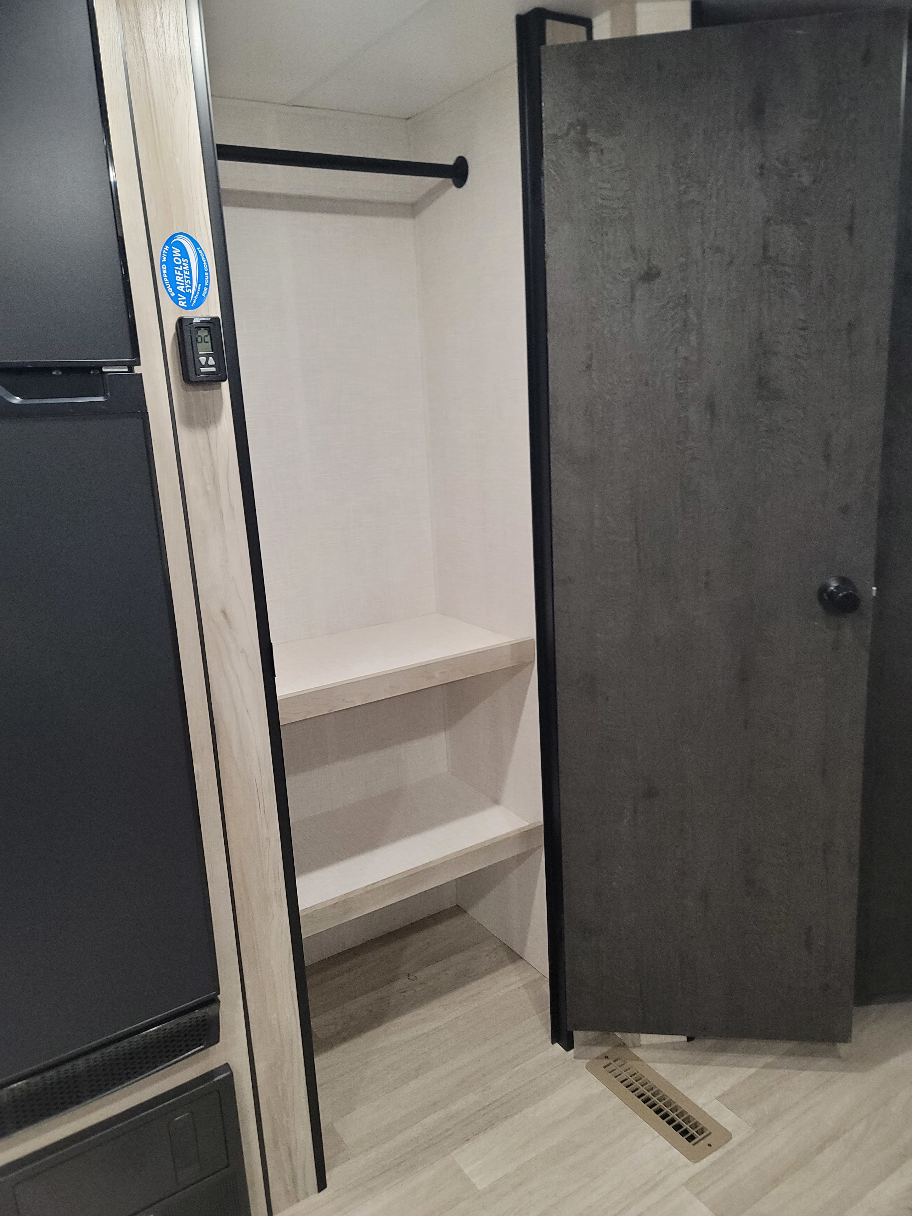 RV rental interior: Open closet with shelves & rod, fridge, thermostat, and floor vent for comfort.. KZ Sportsmen 261BHKSE 261BHKSE 2024