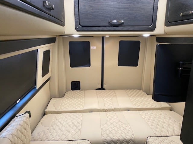 Comfortable RV rental interior showcasing quilted beds, dark wood cabinetry, window shades, and a mounted TV.. Midwest Automotive Designs American Patriot 2023
