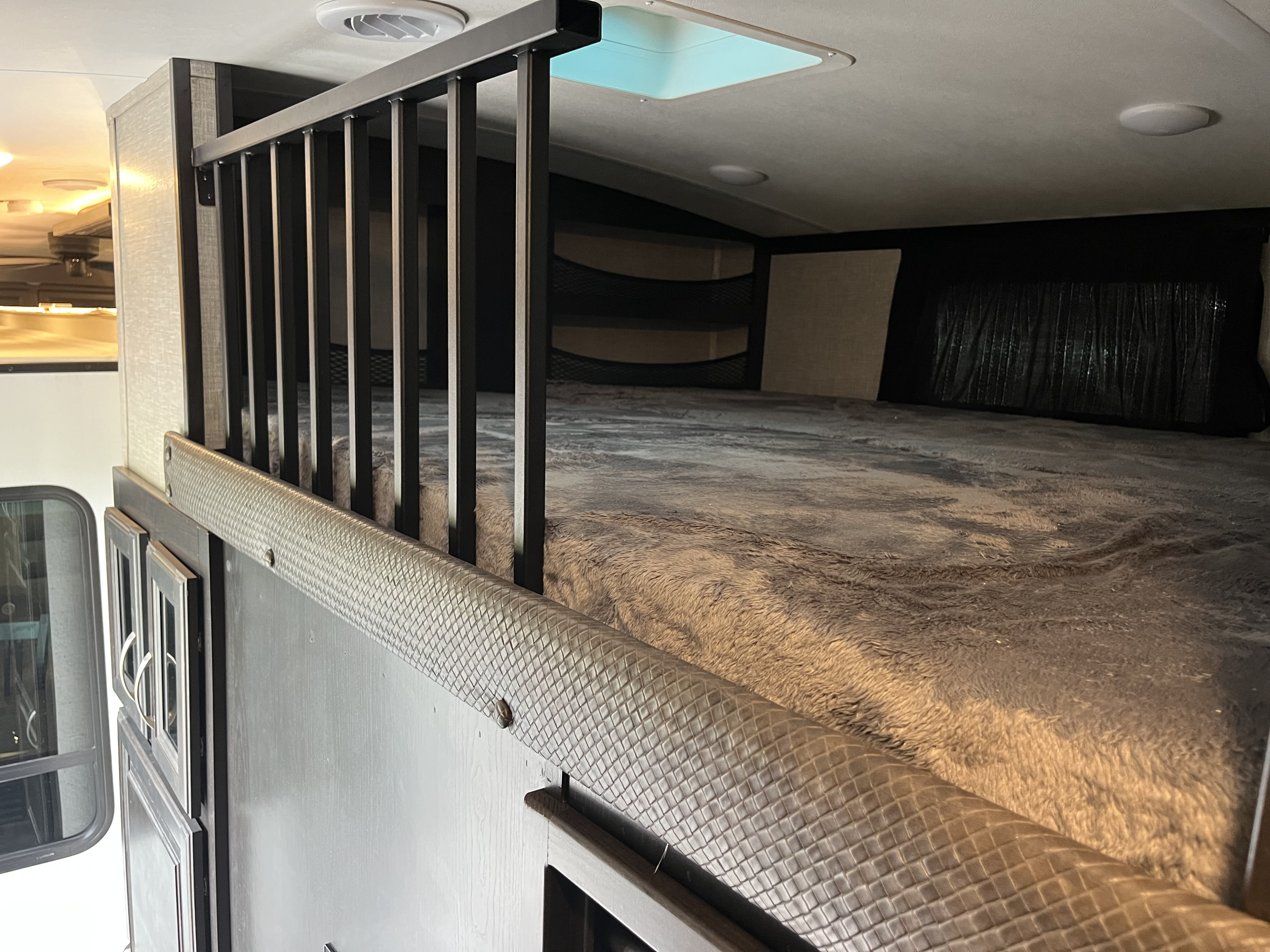 Cozy RV rental bunk bed/loft with a soft blanket, safety railing, and skylight, showing a comfortable sleeping area.. Jayco North Point 2022
