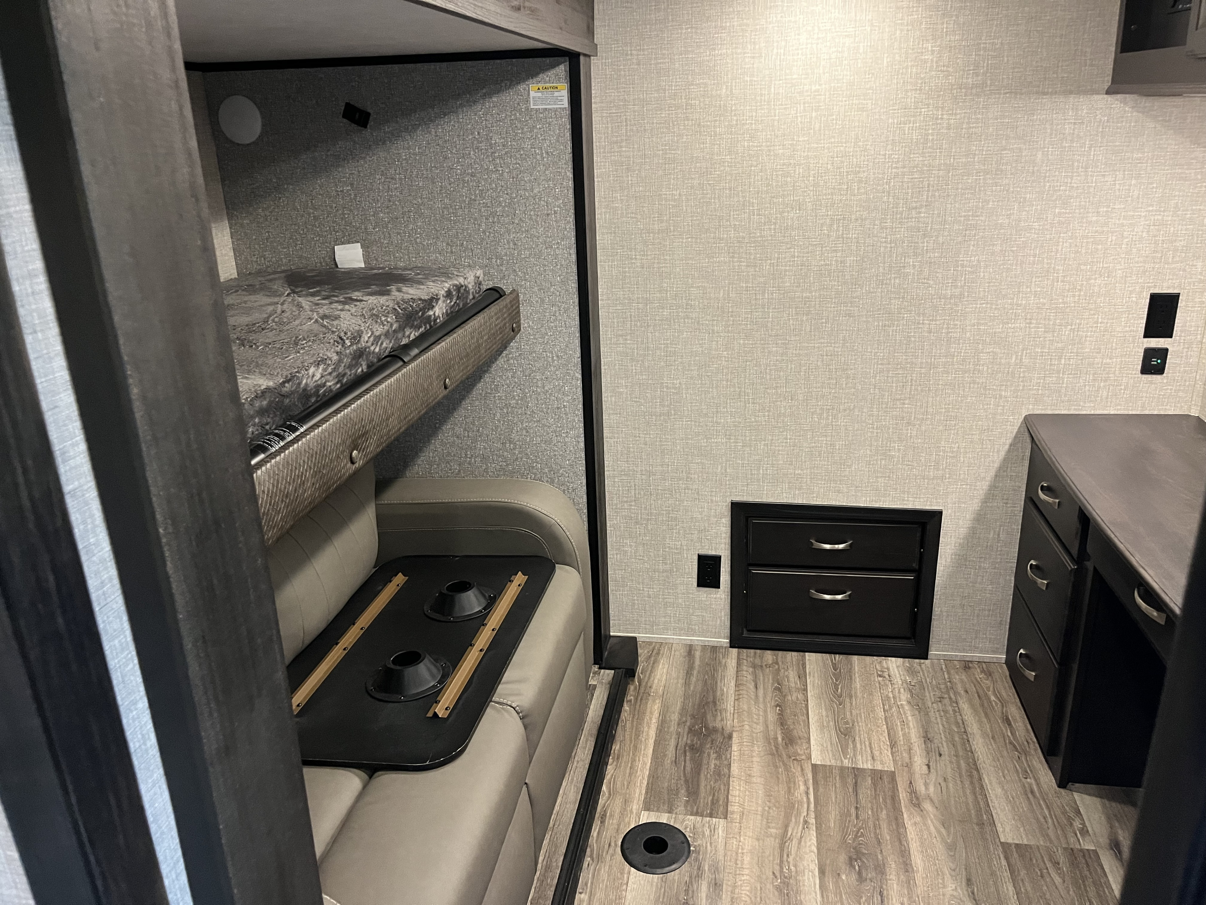 Modern RV rental interior featuring a bunk bed, comfy sofa with table base, and a practical desk/drawer unit.. Jayco North Point 2022