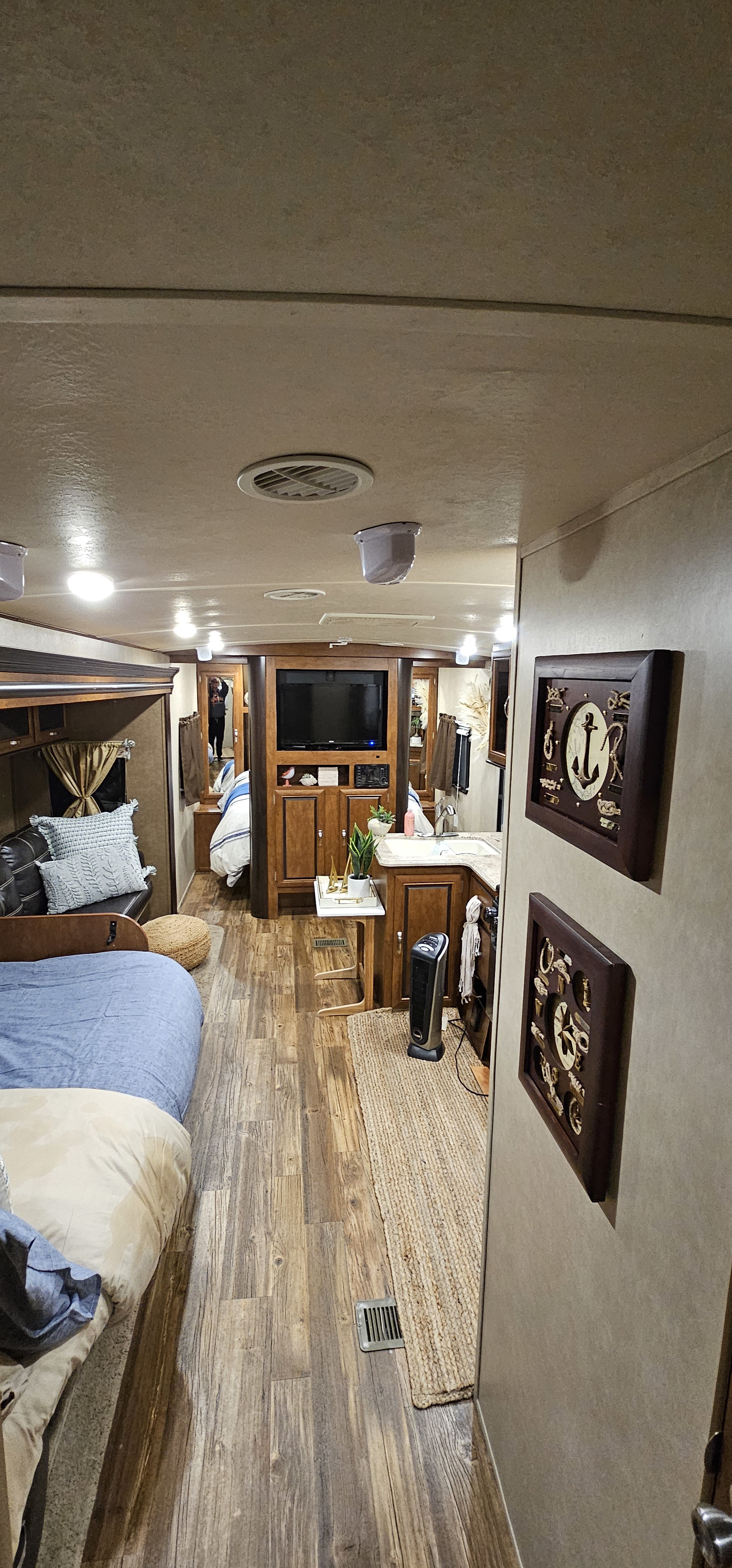 Step inside this cozy RV rental interior. It features a long aisle with wood-look flooring, comfortable beds, a kitchenette, and living area.. Forest River Vibe 2017