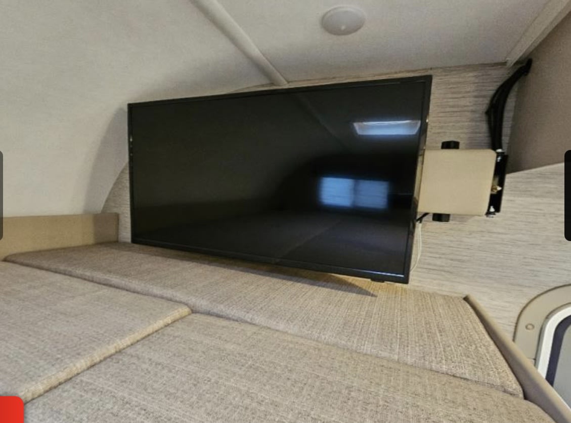Inside this RV rental, find a comfortable bed with a mounted flat-screen TV. Perfect for relaxation and entertainment.. Thor Freedom Elite 2022