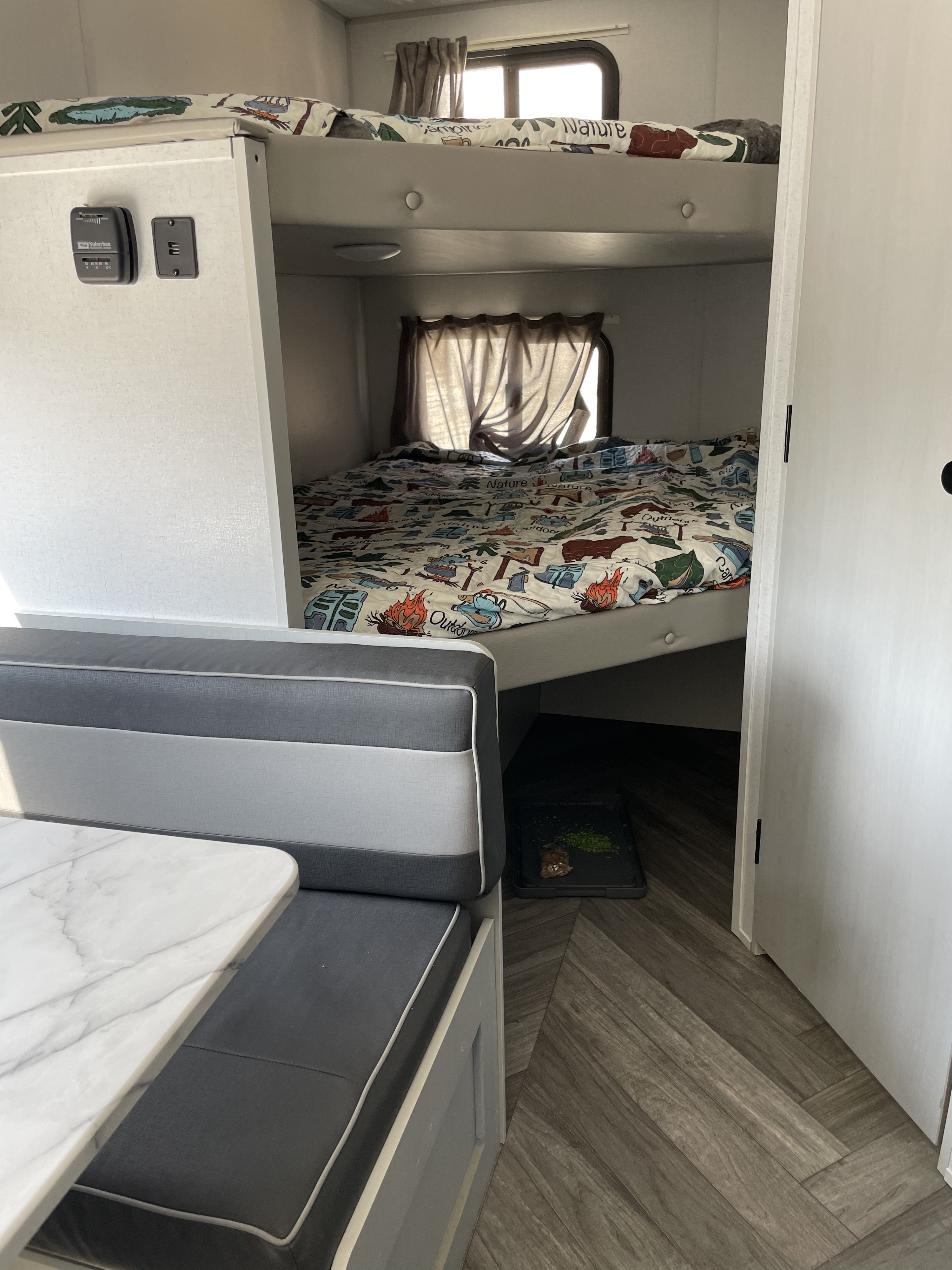 RV rental interior: bunk beds, dining booth with marble-top table, wood floor, and pet mat near bunk.. Forest River Salem FSX PLATINUM 2021