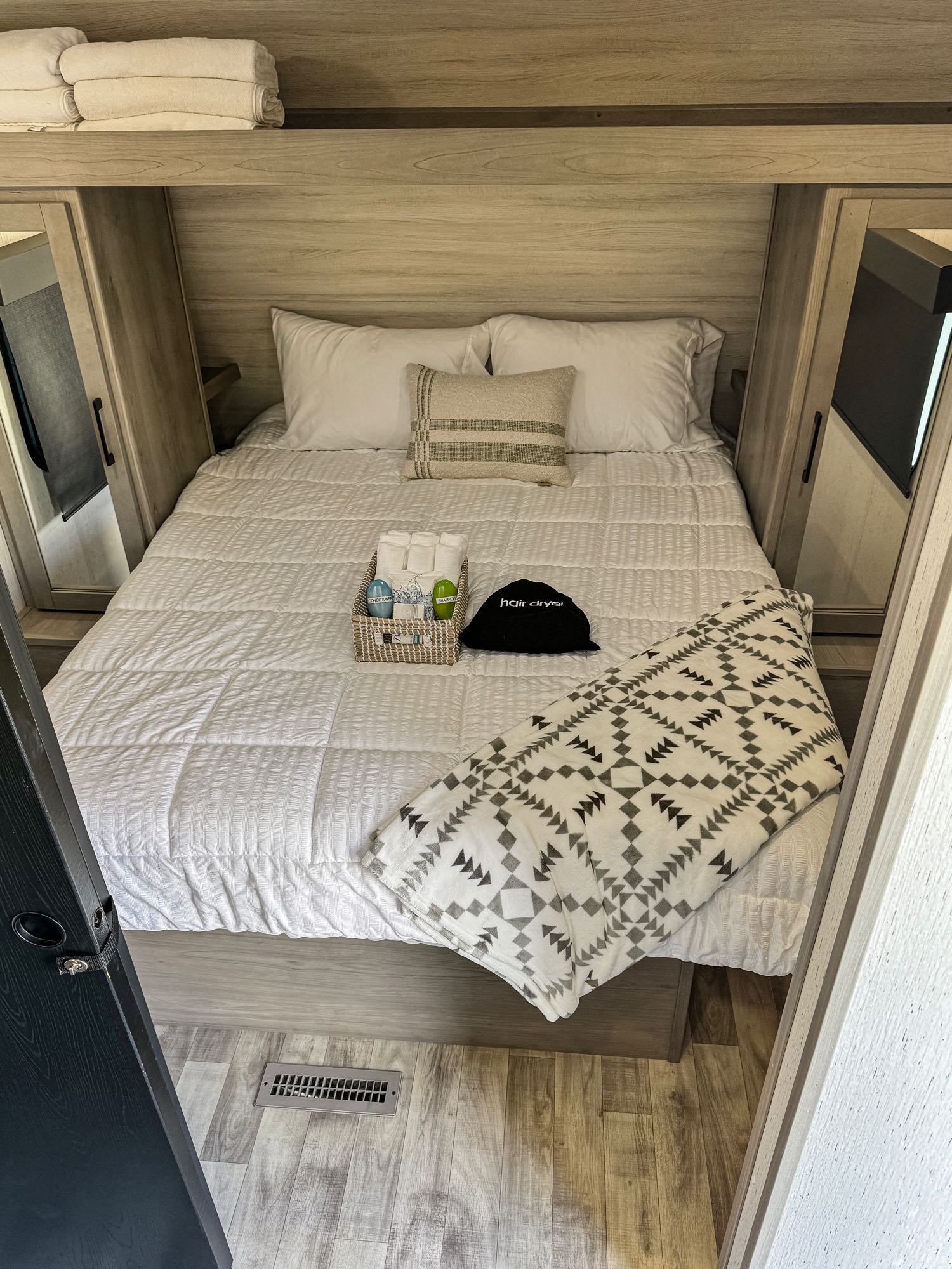 Cozy RV rental bedroom with clean bedding, a basket of toiletries, and a soft blanket, ready for a comfortable stay.. Dutchmen Kodiak SE 2022