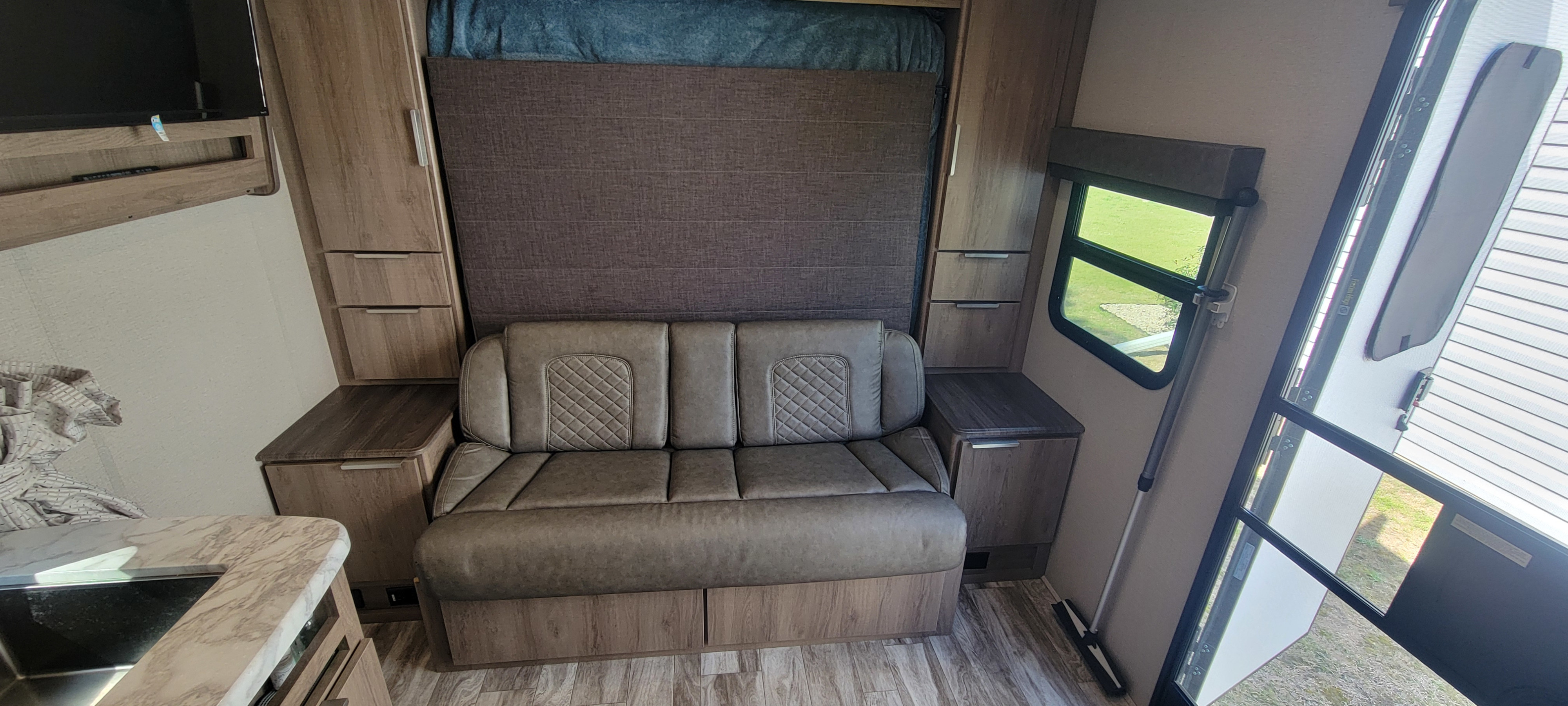 Inside an RV rental: a comfy living space with convertible sofa, kitchen, TV, & storage. Ideal for road trips.. Grand Design Imagine XLS 2021