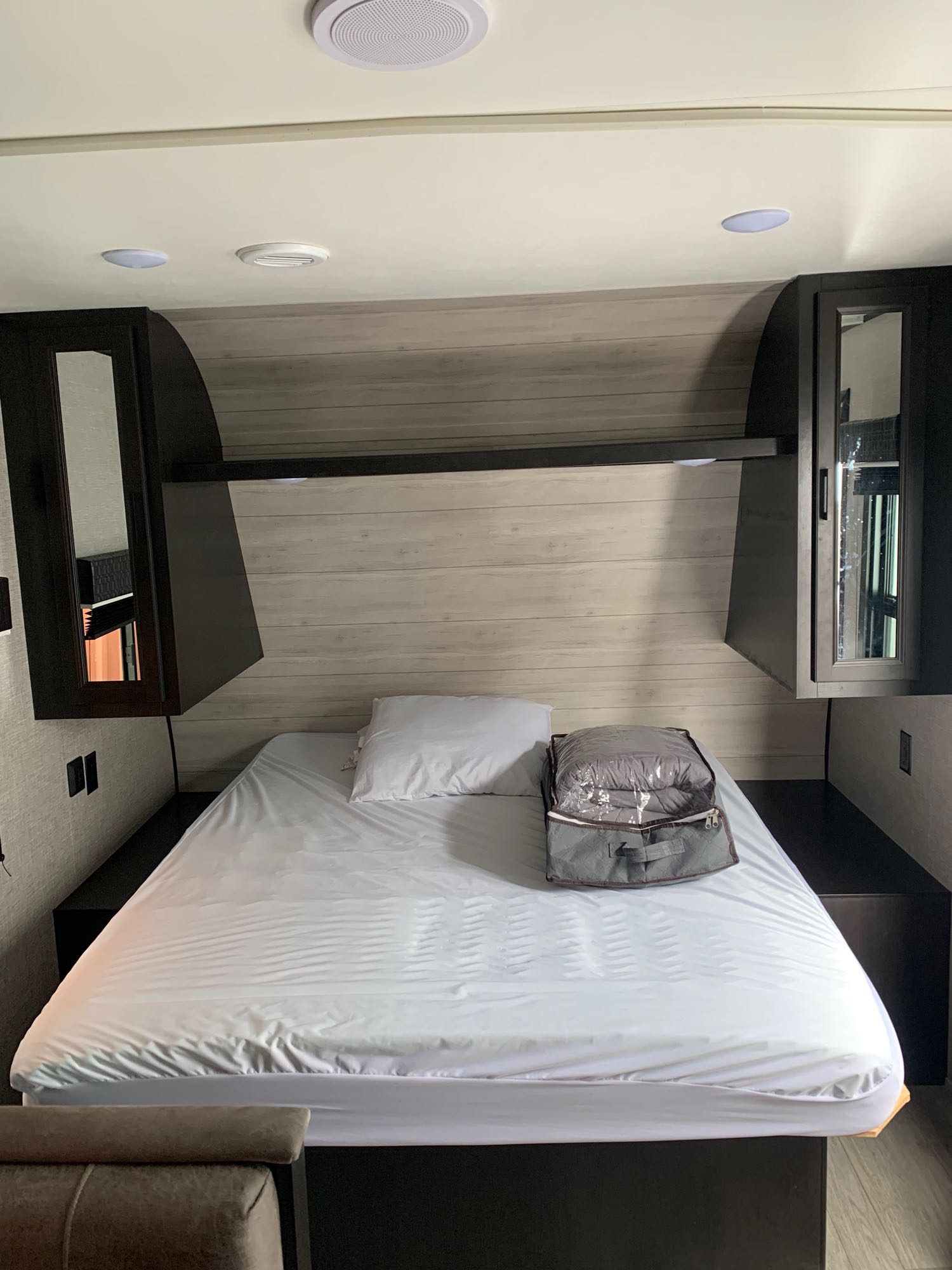 RV rental bedroom: A neatly made bed with white linens, overhead cabinets, and built-in lighting in a compact space.. Jayco Jay Flight 2022