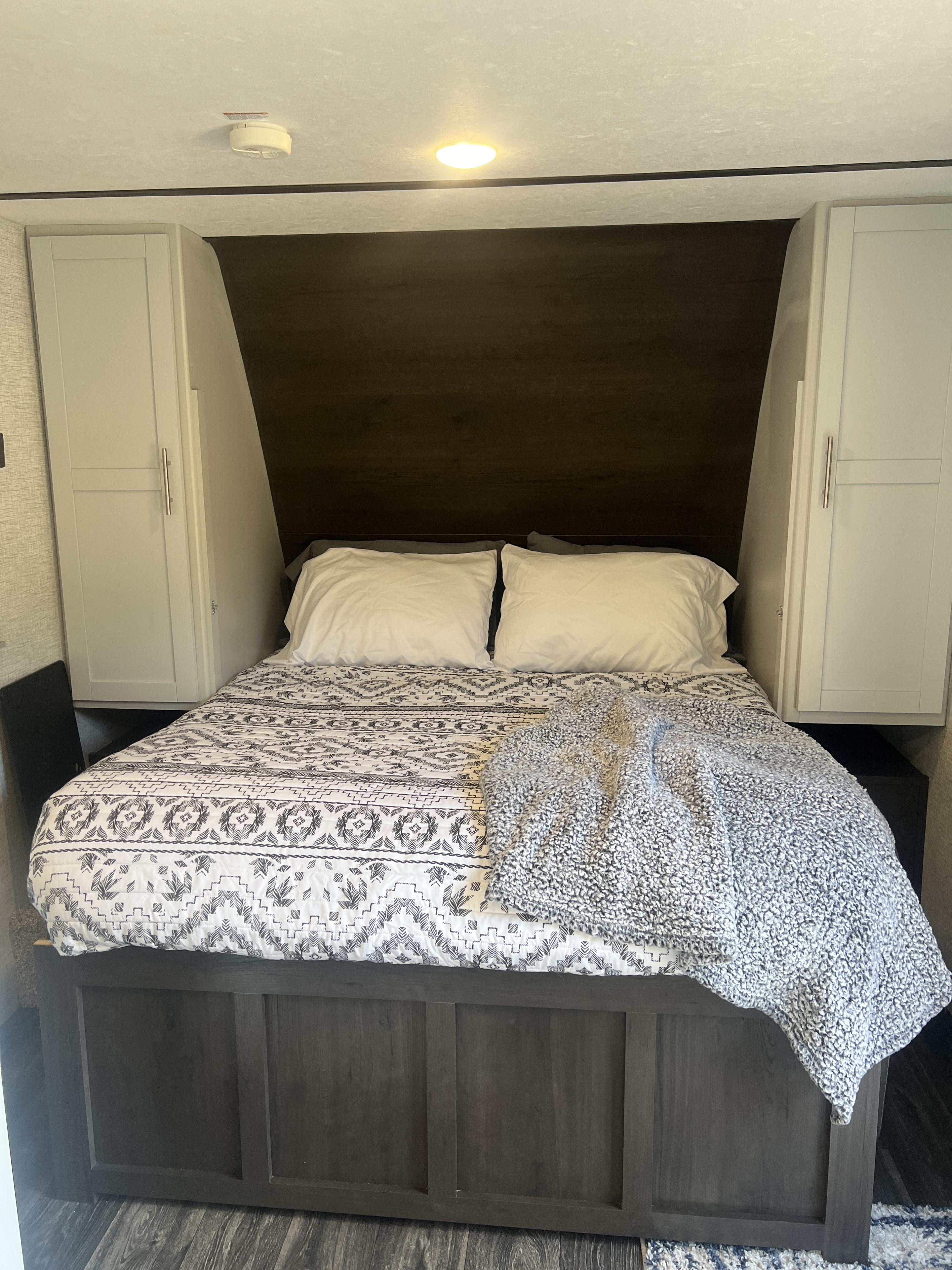 RV rental bedroom: A cozy sleeping space with a comfortable bed, white pillows, and modern cabinet storage.. Keystone RV Bullet Crossfire 2021