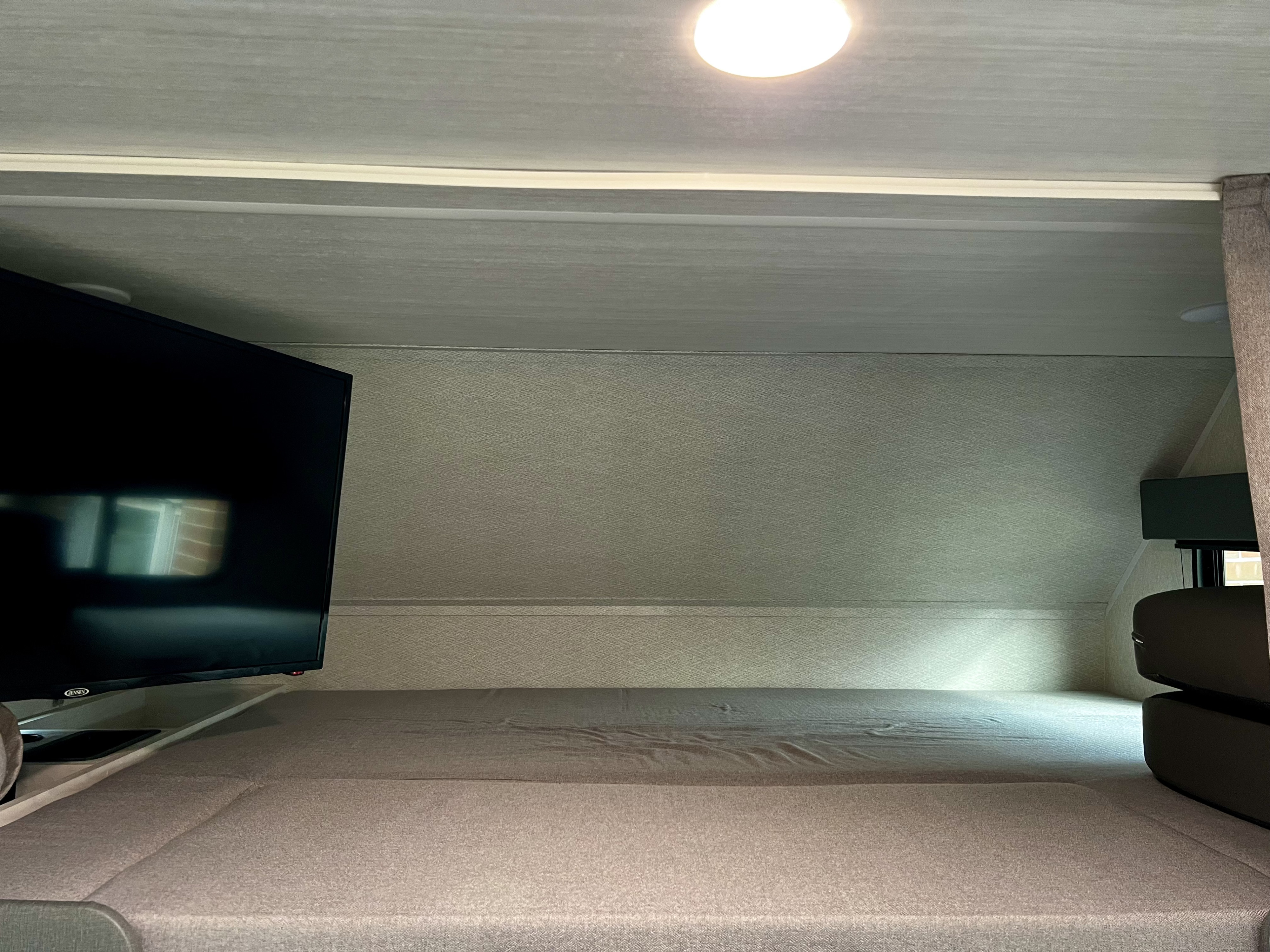 Overhead sleeping area in an RV rental, featuring a mounted TV and soft bedding for travel comfort.. 1FDXE4FN9RDD14726 3100FB 2023