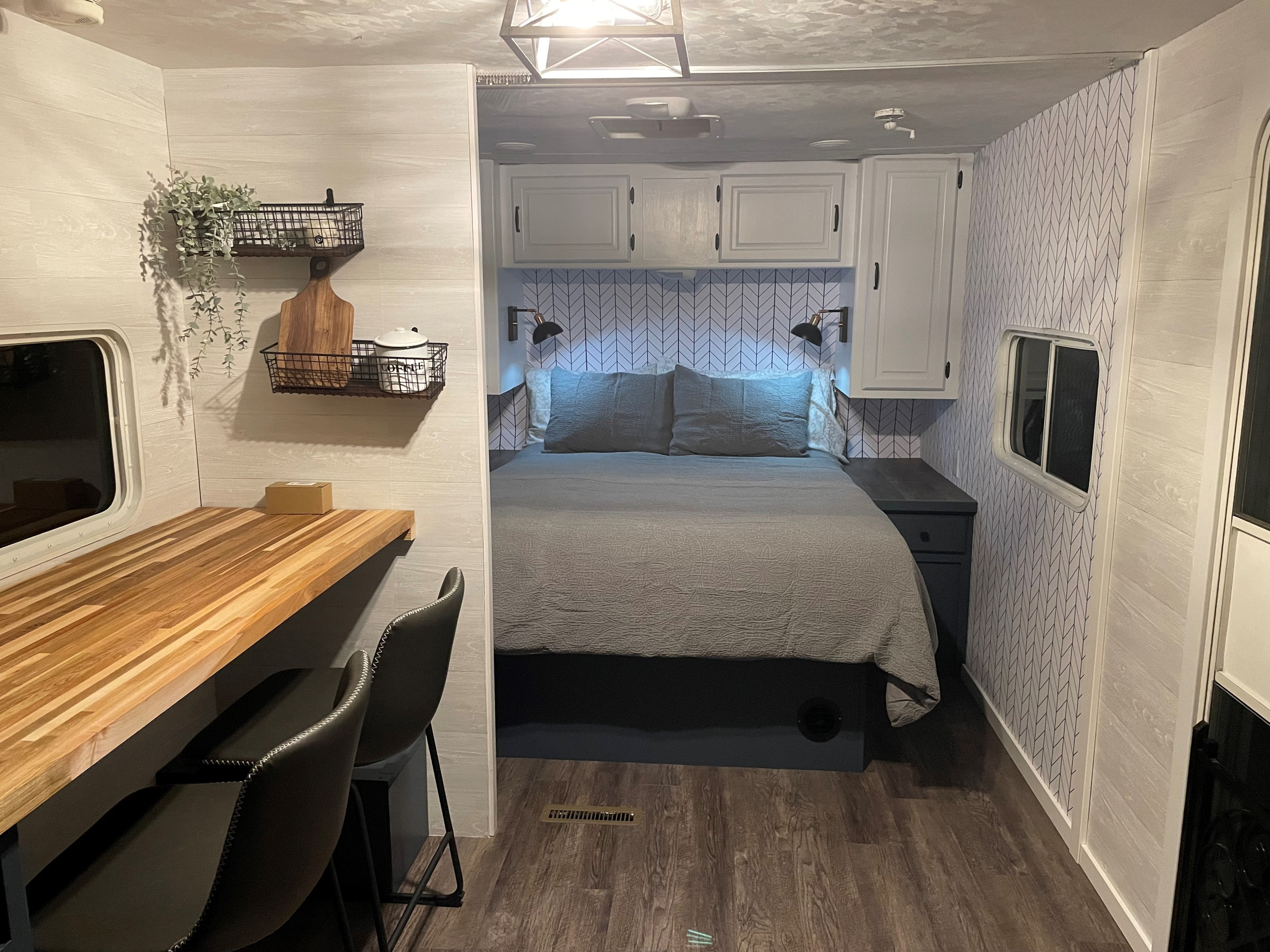 Modern RV rental with a cozy bedroom featuring a chevron accent wall, wood desk, and stylish decor for comfortable travel.. Forest River Wildwood 2011