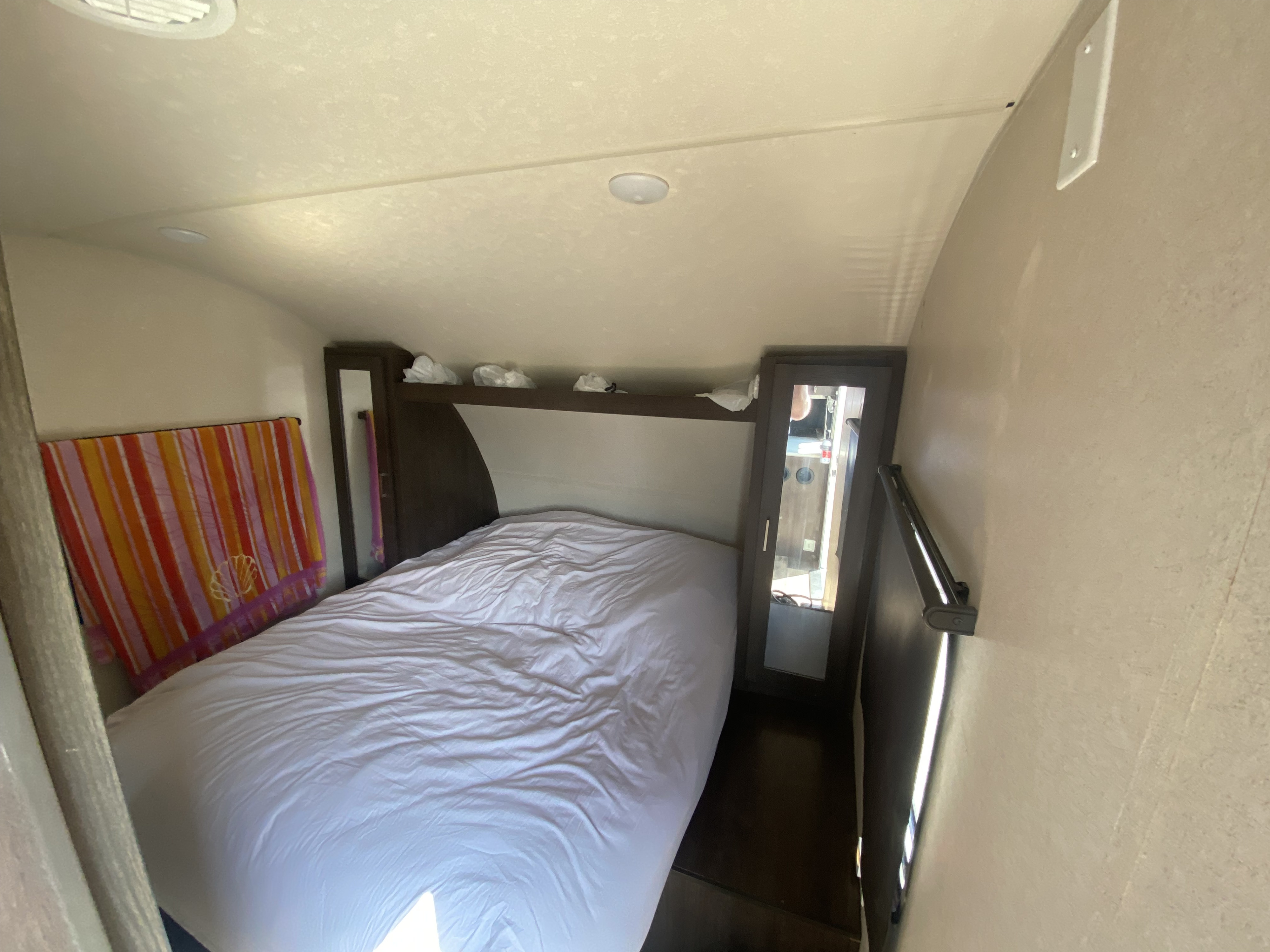 Cozy RV rental bedroom with a white bed, mirrored closets, and overhead storage. Perfect for travel comfort.. Forest River Wildwood X-Lite 2019