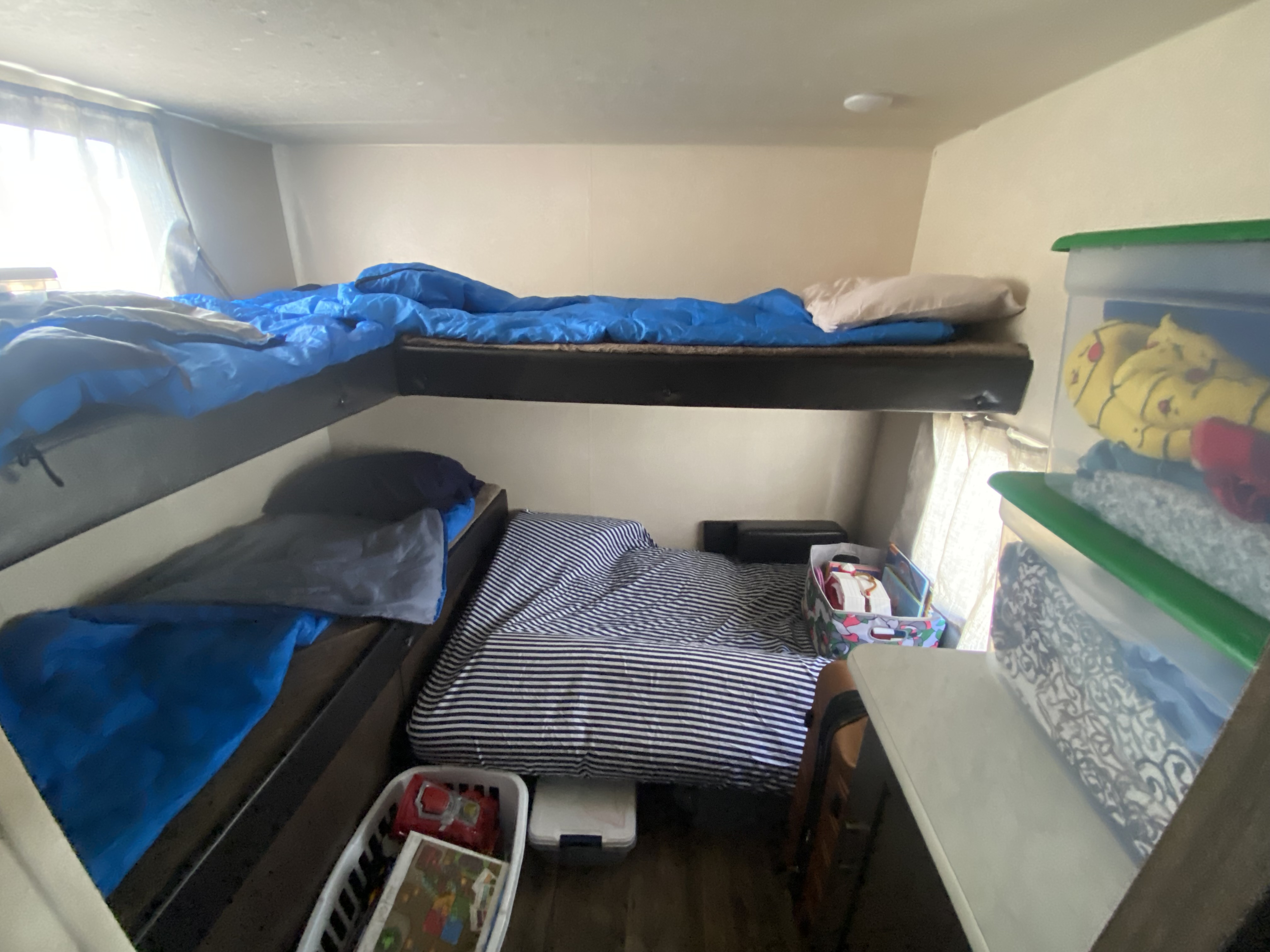 RV rental interior: bunk beds with blue and striped bedding, plus clear storage bins for a compact space.. Forest River Wildwood X-Lite 2019