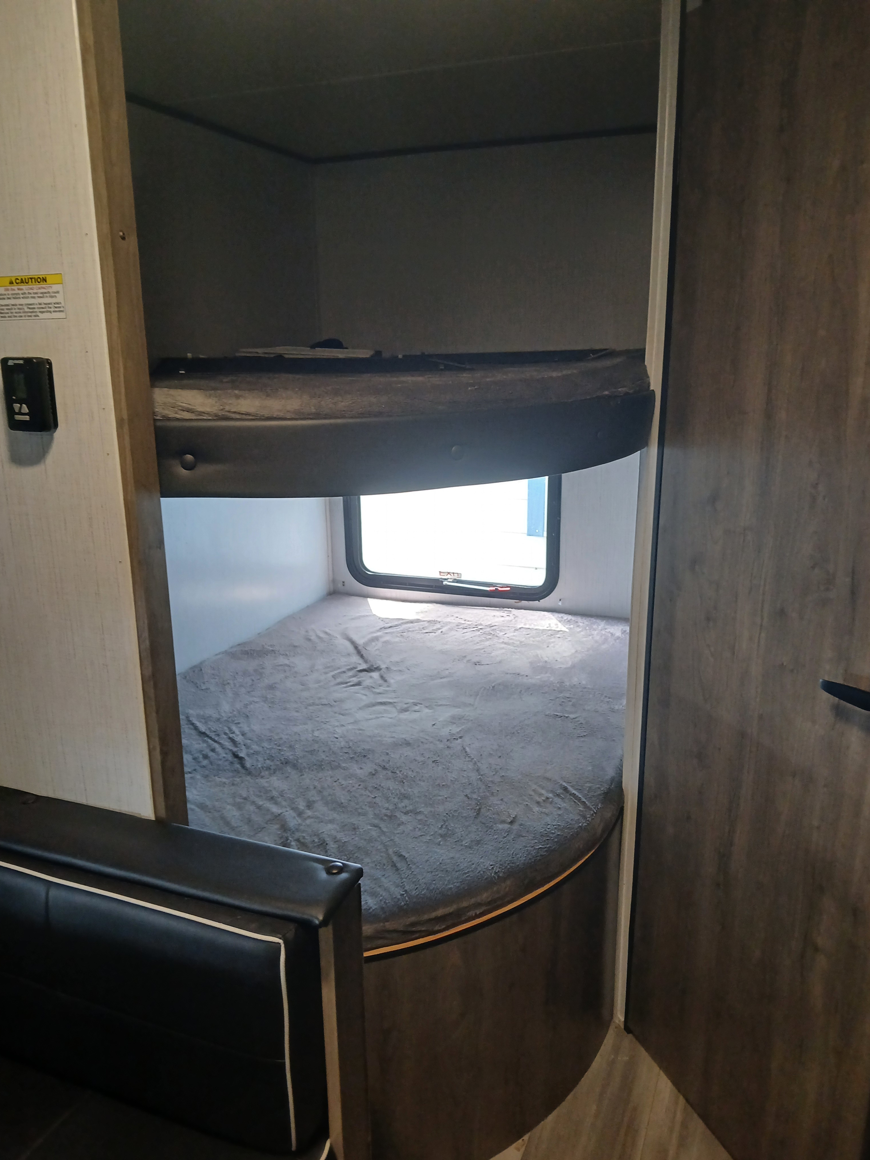 RV rental interior featuring built-in bunk beds with a window, and a black seating area. Cozy sleeping space.. Heartland RVs Pioneer 2022