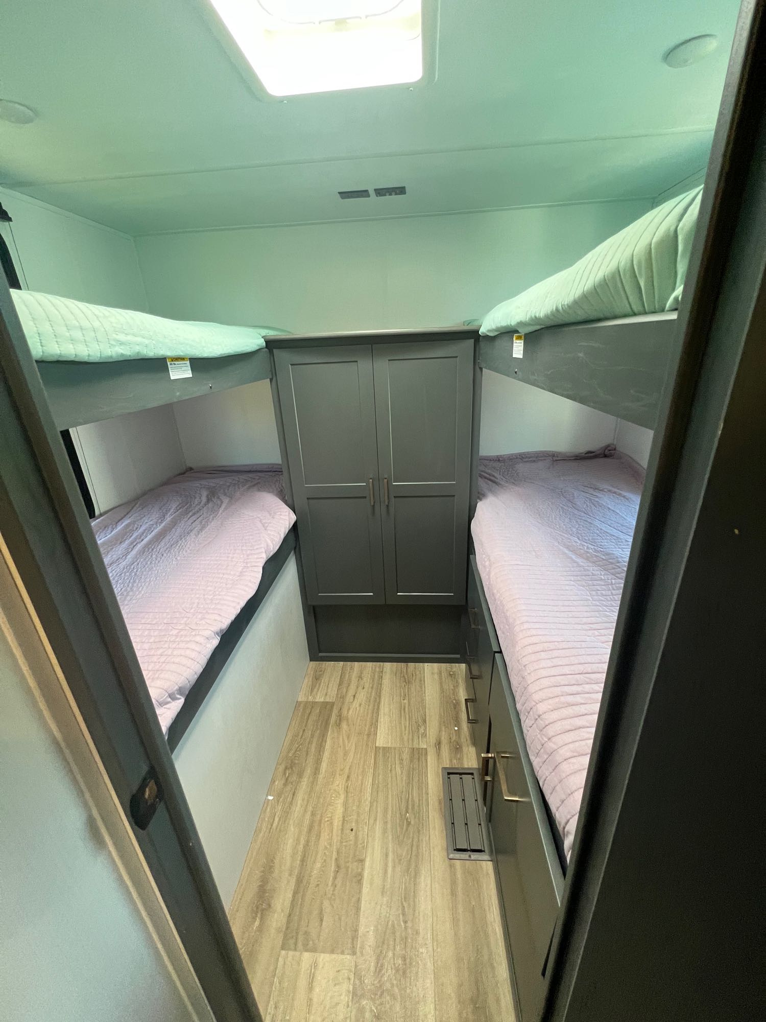 RV rental's bunk room with upper green and lower purple beds, plus a central wardrobe and drawers for storage.. Keystone Bullet Crossfire 4YDTBLN25RD430760 2024