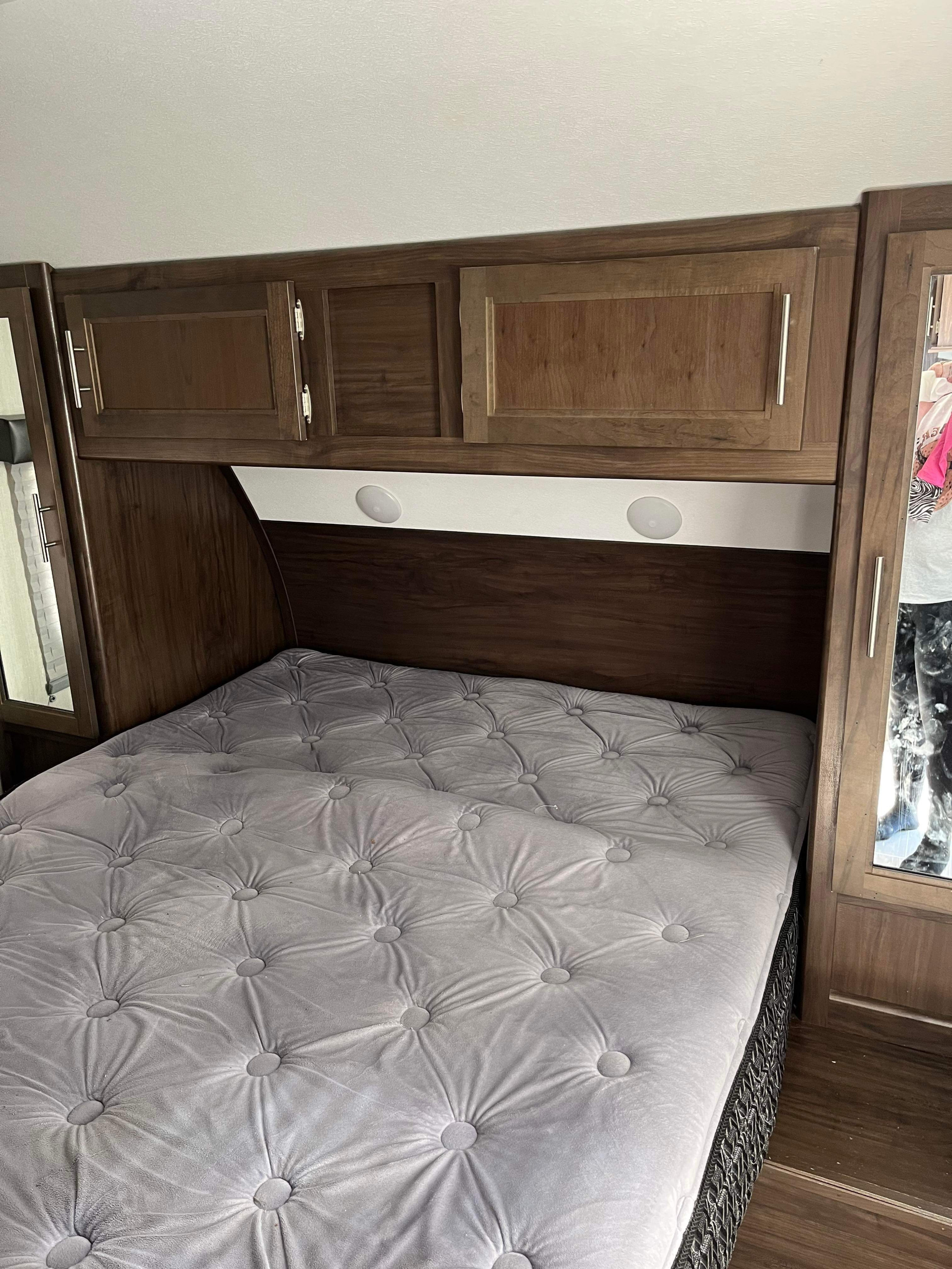 An RV rental bedroom: tufted grey bed, dark wood cabinets, and integrated lighting for a cozy interior.. Forest River Cherokee Grey Wolf 2020