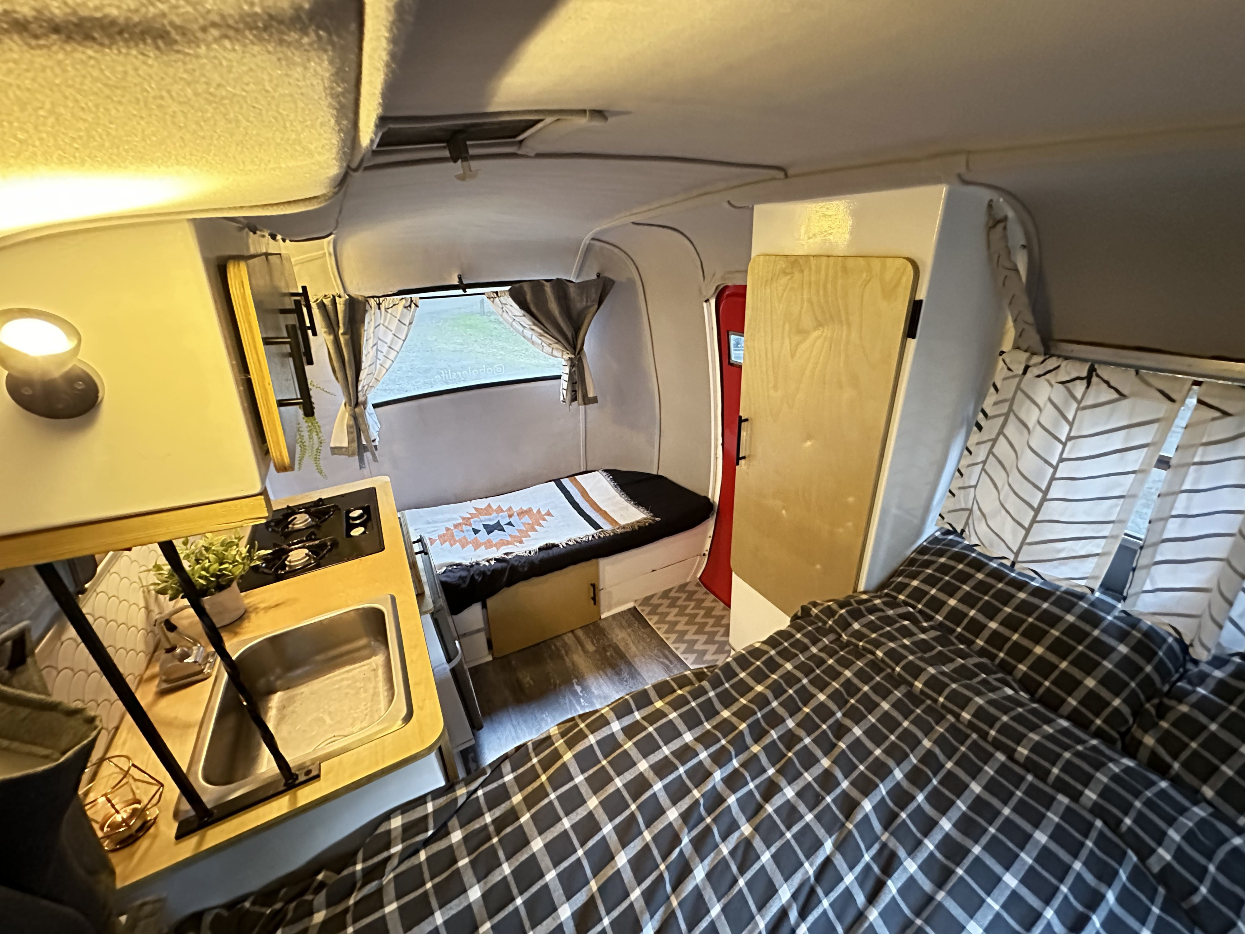 Cozy RV rental interior featuring a compact kitchen, two beds, and patterned bedding, ideal for travel adventures.. Boler 1978 Boler 1978