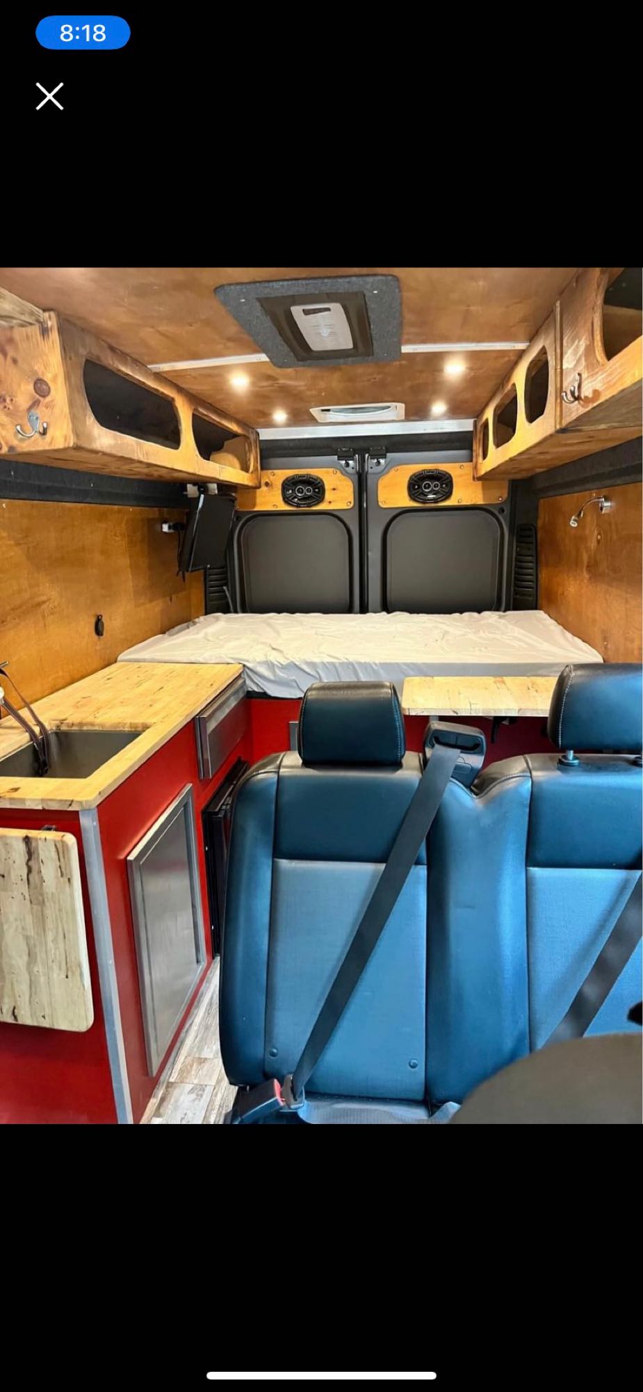 Explore this custom RV rental interior: wood-paneled walls, a rear bed, kitchen, and passenger seating.. Ram Pro-master 2019