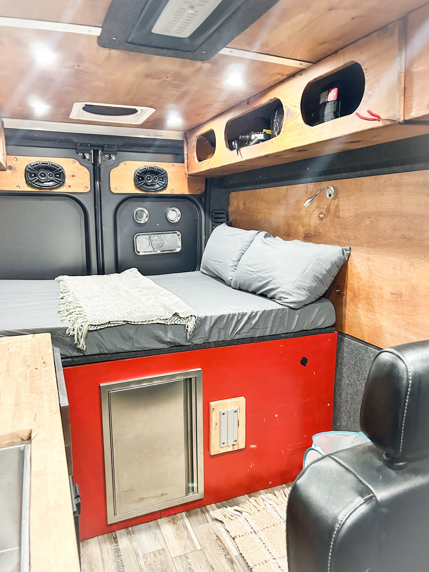 This RV rental offers a cozy bed, kitchen sink, and smart storage in a wood-paneled, custom camper van.. Ram Pro-master 2019