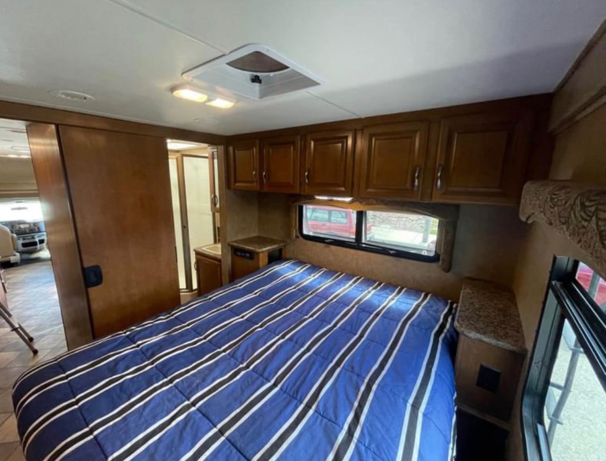 RV rental: Interior shot of a cozy bedroom with blue striped bed, overhead cabinets, and side window.. Forest River four winds 2016